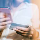 Young woman shopping online with smartphone and credit card on hand.