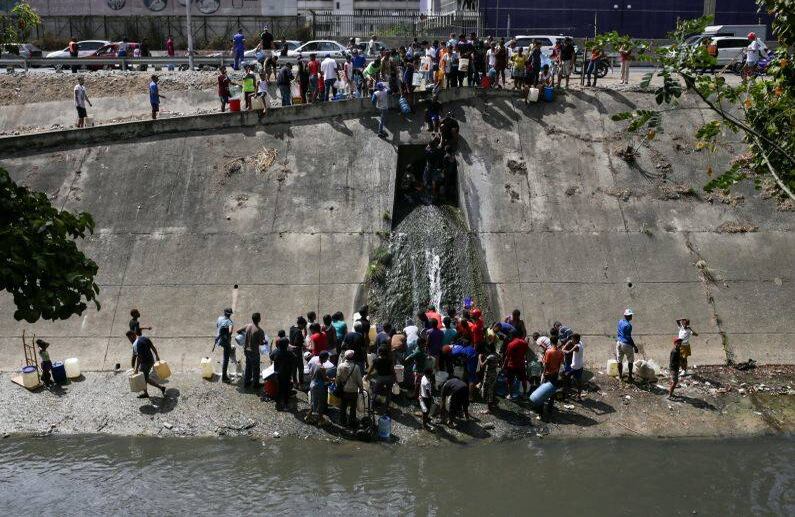 El apagón y el desabastecimiento de agua ha llevado a los venexolanos a recolectan agua de tuberías y ríos. FOTO: Cristian HERNANDEZ/AFP