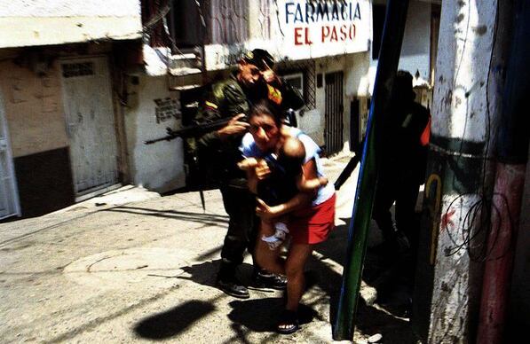 Atrapados en combate En la Comuna 13, de Medellín, una mujer y un niño buscan refugio durante un enfrentamiento entre soldados del Ejército y milicianos de las FARC. Este combate tuvo lugar en 18 de octubre de 2002. Foto: Stephen Ferry.