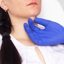 El cosmetólogo del médico comprueba la piel para la elasticidad en una barbilla doble en una niña, primer plano, cosmetología, resiliencia, problema