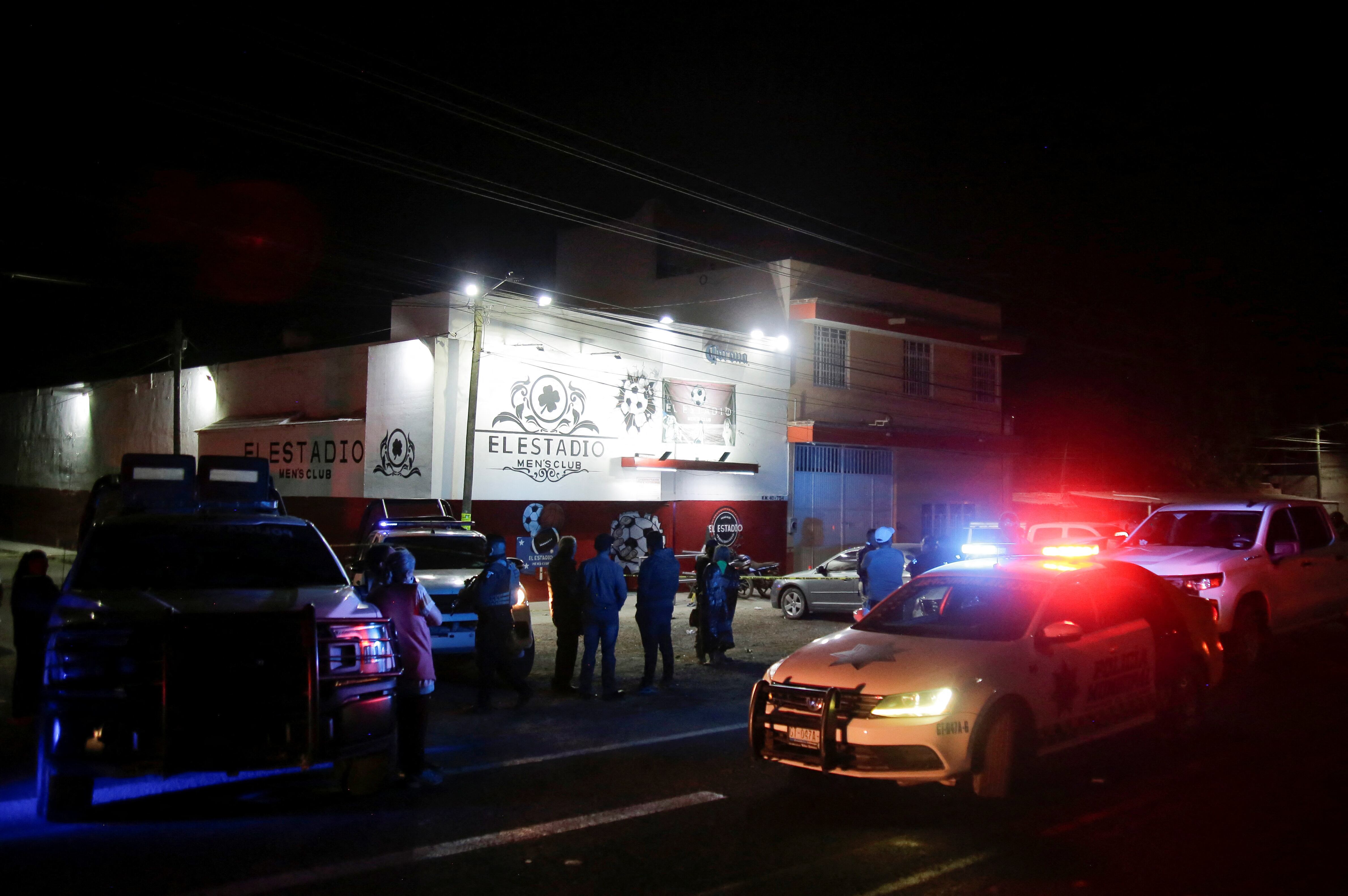 Miembros de las fuerzas de seguridad y transeúntes se encuentran afuera de un club nocturno donde los clientes fueron asesinados y otros heridos por un grupo armado no identificado que abrió fuego contra las personas, en Apaseo El Grande, en el estado de Guanajuato, México