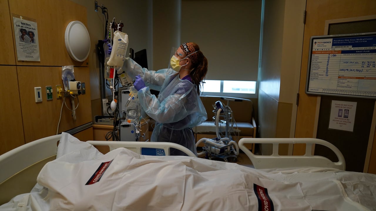 La enfermera Nikki Hollinger limpia una habitación frente al cuerpo de una víctima de covid-19 en un centro médico de Los Ángeles. (AP Foto/Jae C. Hong)