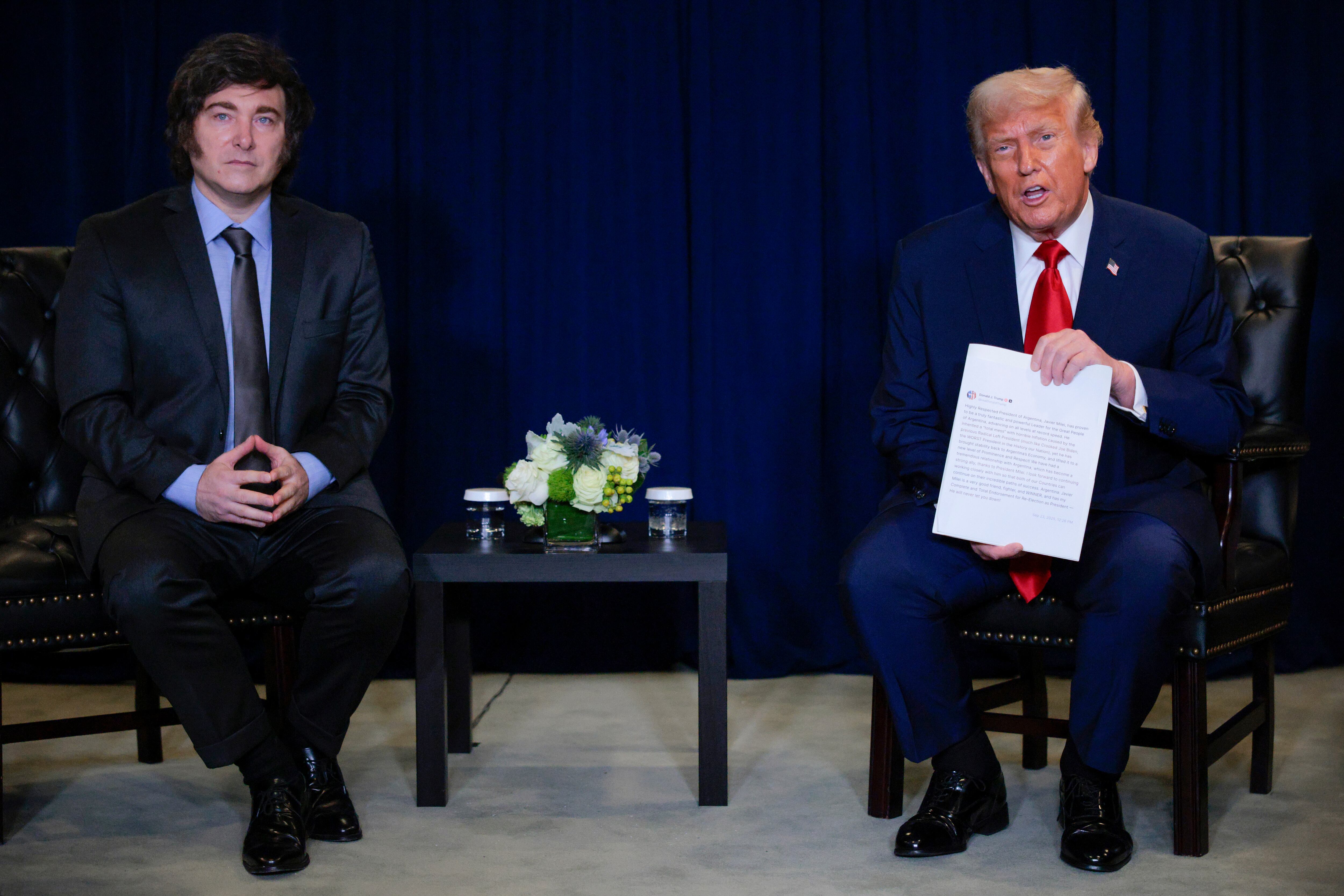 El presidente de Estados Unidos, Donald Trump (der.), sostiene una copia impresa de su publicación en redes sociales mientras conversa con el presidente de Argentina, Javier Milei, durante una reunión bilateral en el marco del 80.º periodo de sesiones de la Asamblea General de las Naciones Unidas (AGNU) en la sede de las Naciones Unidas el 23 de septiembre de 2025 en la ciudad de Nueva York.