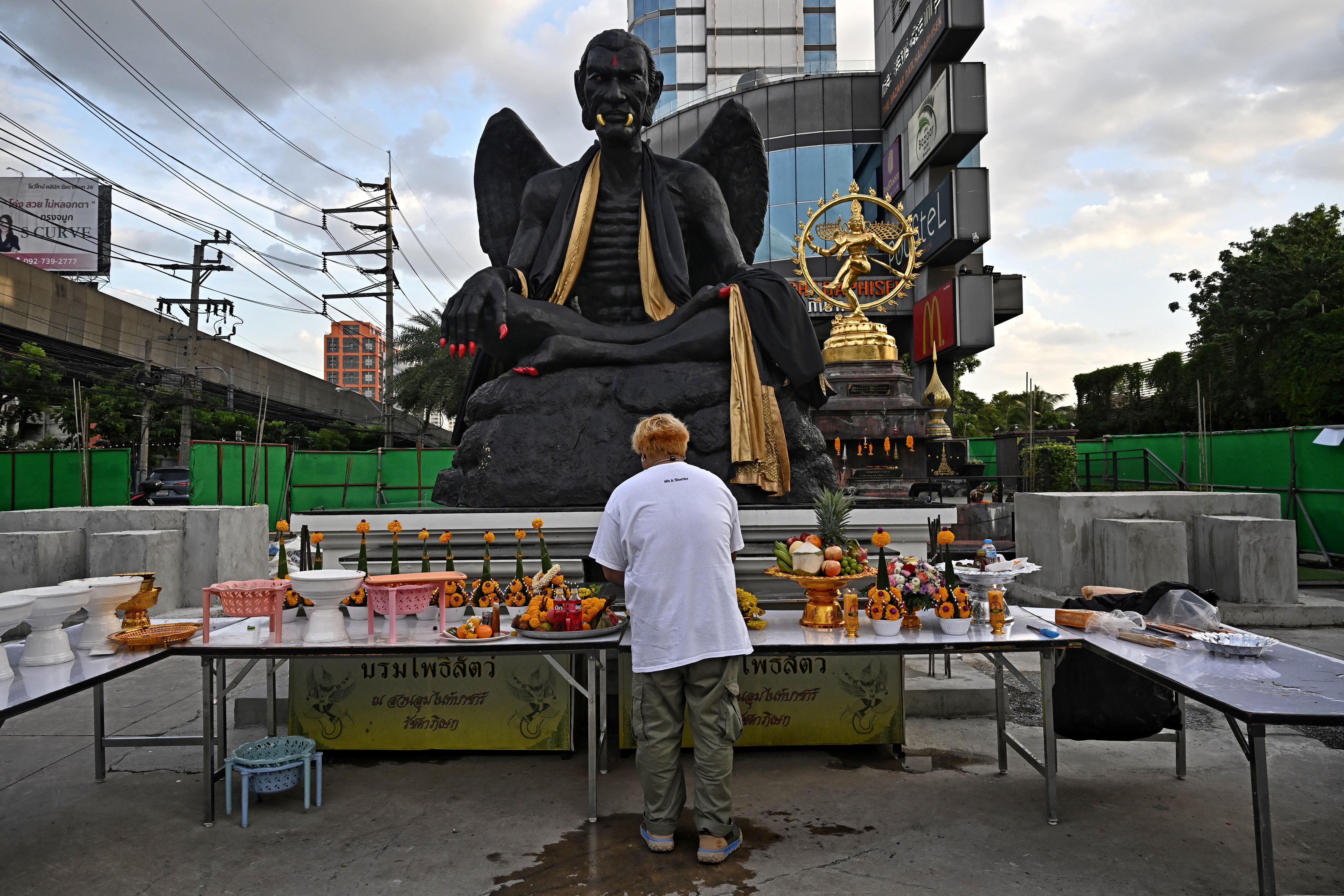 Una enorme estatua negra de un demacrado, alado figura con colmillos dorados y garras escarlatas mira hacia abajo en una concurrida calle de Bangkok, su repentina aparición activa la alarma y pide su eliminación. (Foto de Lillian SUWANRUMPHA / AFP)