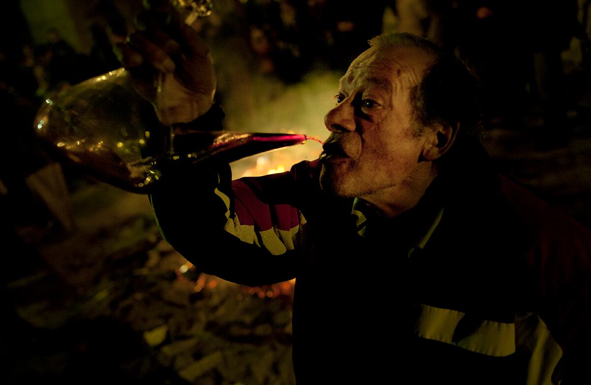 Un hombre toma vino de un ‘Porrón’ mientras, en España, se celebra la noche de Santa Lucía, la santa de la luz, con música, comida y fogatas. (AP)