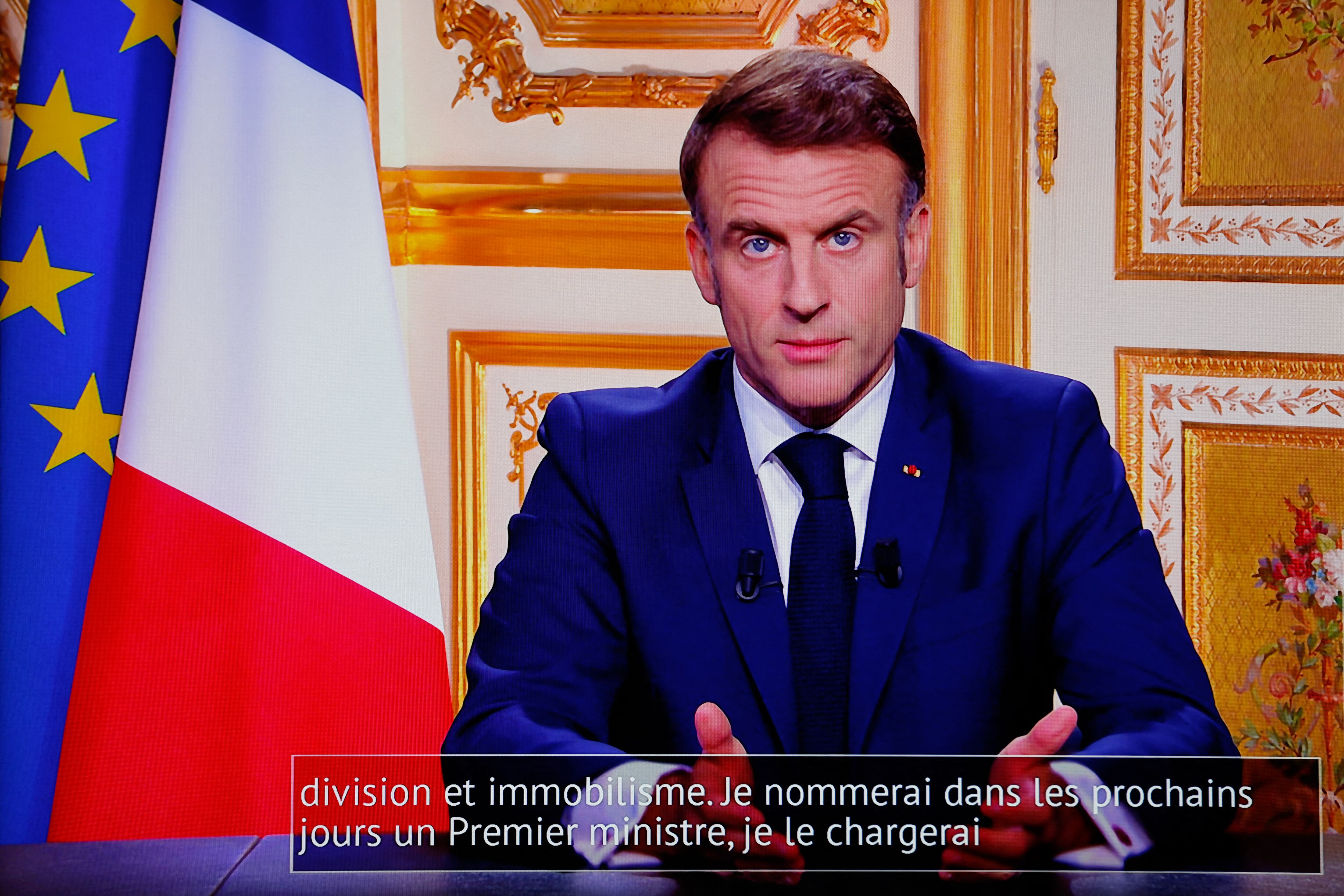 El presidente francés, Emmanuel Macron, aparece en monitores junto con leyendas que dicen "Nombraré un nuevo Primer Ministro en los próximos días", en una sala de control de la sede de la AFP mientras se dirige a la nación durante una transmisión televisada desde el Palacio presidencial del Elíseo, el lunes. el día de la dimisión del Primer Ministro, el 5 de diciembre de 2024, tras la derrota parlamentaria del día anterior, que obligó a su gobierno a dimitir.