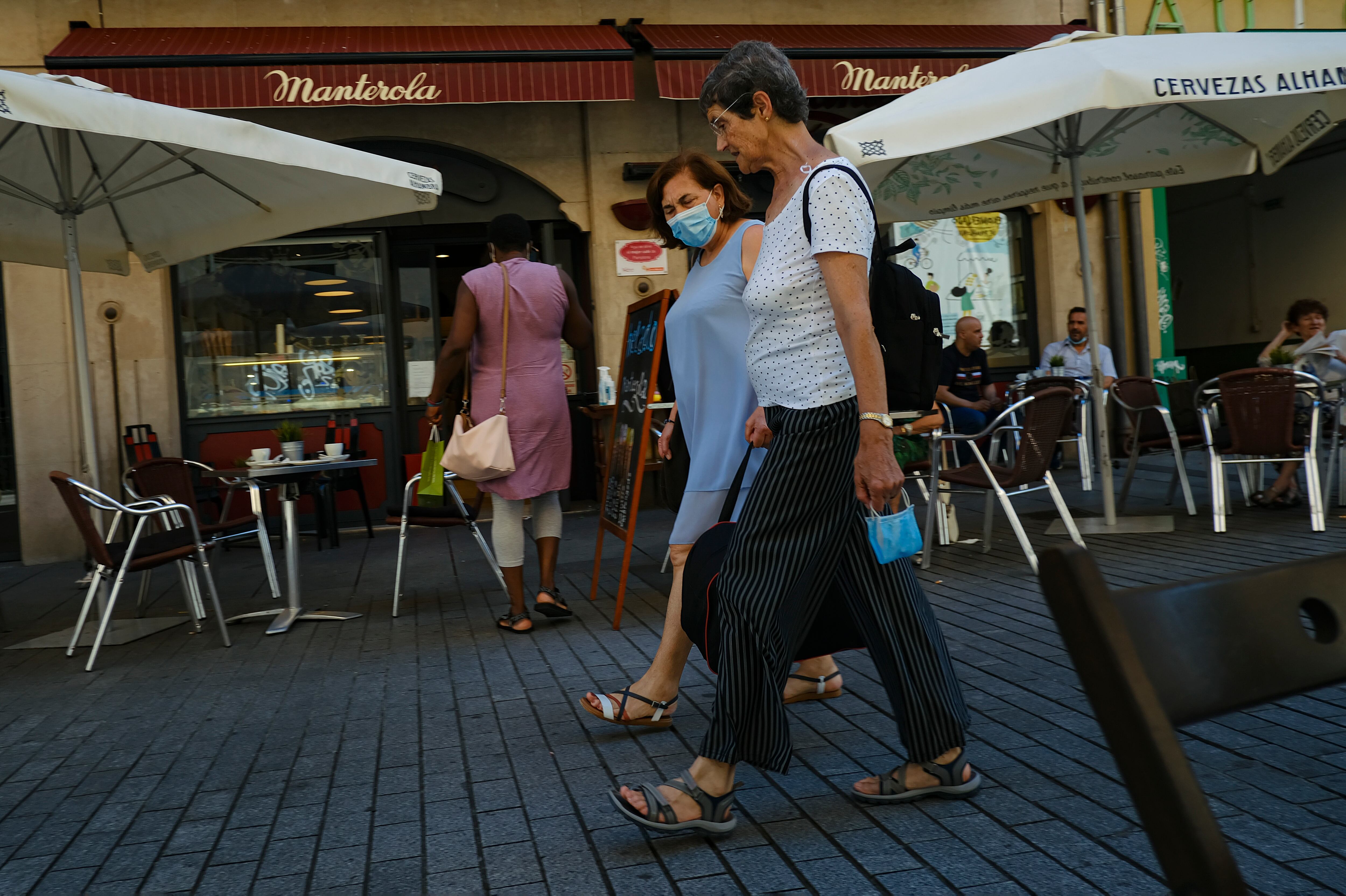 Dos mujeres caminan cerca de un bar en Pamplona, norte de España, el 5 de julio de 2021. (AP Foto/Alvaro Barrientos)