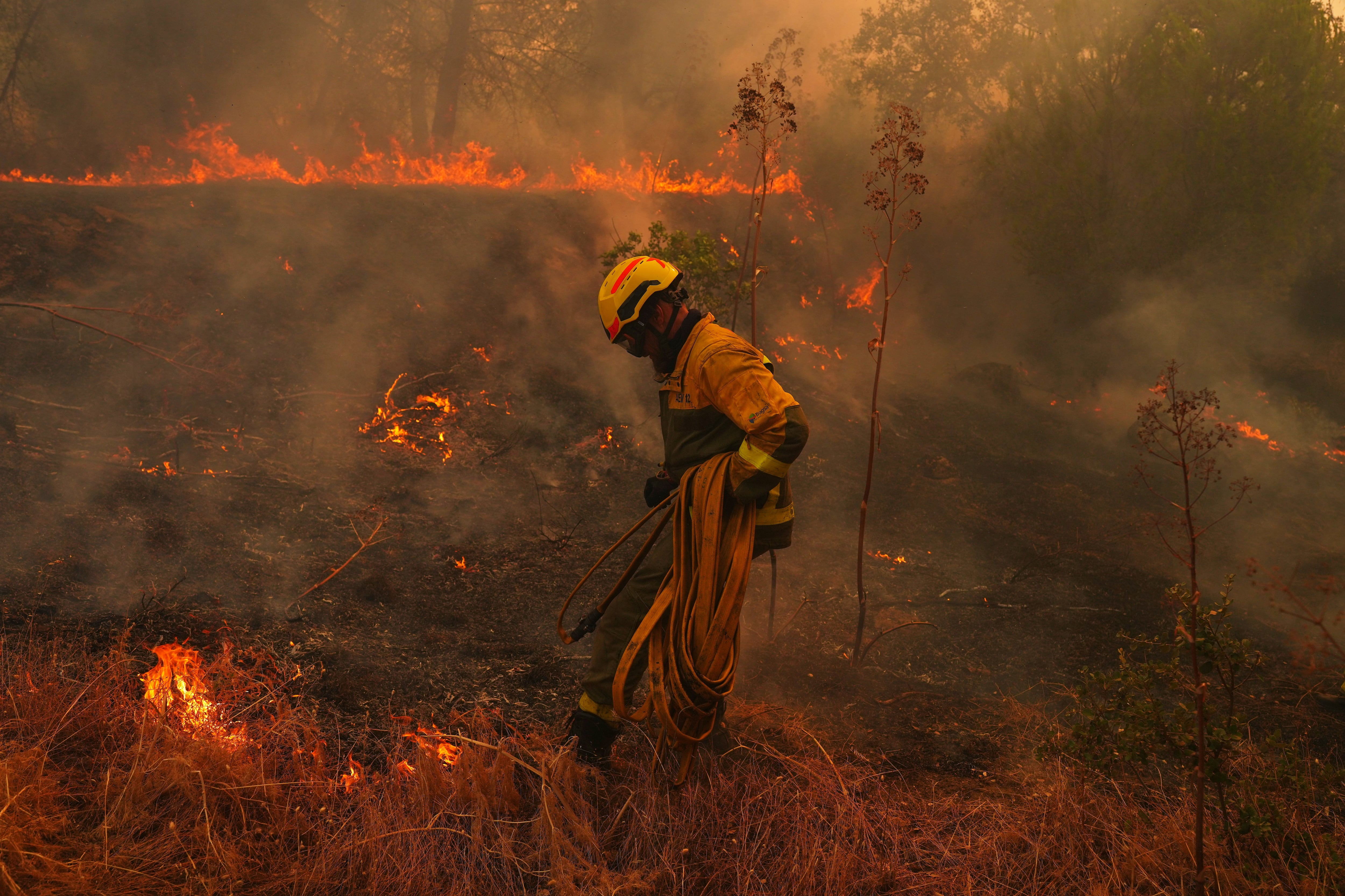 Un bombero transporta una manguera mientras combate un incendio forestal en San Martín de Valdeiglesias, al oeste de Madrid, España.
