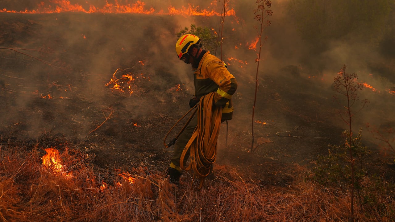 Un bombero transporta una manguera mientras combate un incendio forestal en San Martín de Valdeiglesias, al oeste de Madrid, España.
