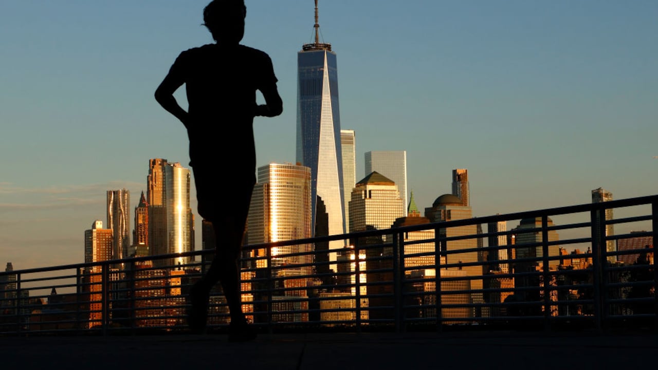 El sol se pone en el horizonte del bajo Manhattan y el One World Trade Center en la ciudad de Nueva York mientras una persona trota a lo largo del río Hudson el 31 de agosto de 2023, en Jersey City, Nueva Jersey. (Foto de Gary Hershorn/Getty Images)