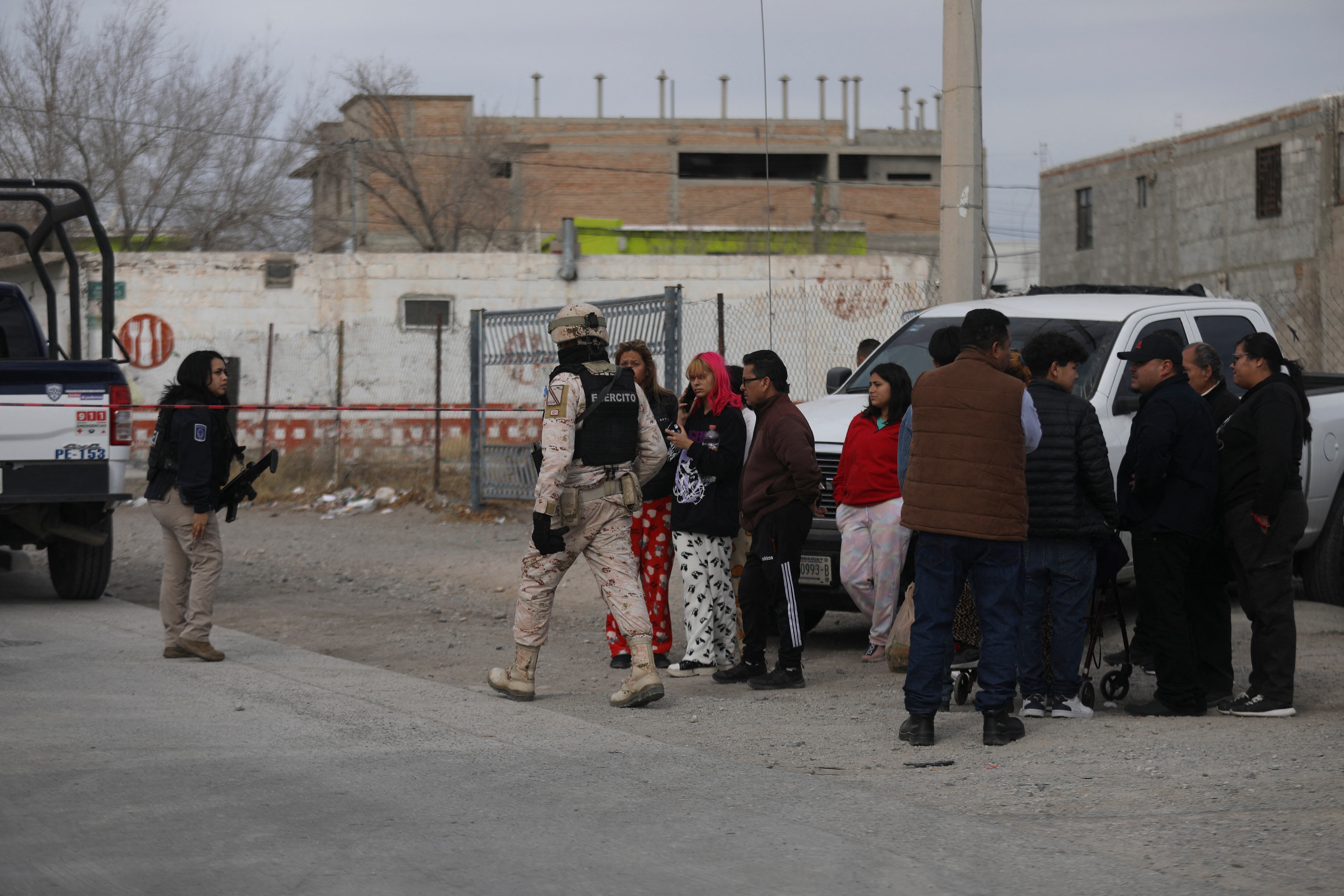 Familiares de reclusos (derecha) junto a miembros del Ejército Mexicano asegurando un área fuera de la prisión número 3 de Ciudad Juárez después de un ataque en Ciudad Juárez, estado de Chihuahua, el 1 de enero de 2023. - Hombres armados atacaron una prisión en el norte de México ciudad de Ciudad Juárez el domingo, dejando 14 muertos y permitiendo la fuga de 24 reclusos, informó la fiscalía del estado de Chihuahua. Un número desconocido de hombres armados a bordo de vehículos blindados participó en el ataque, y entre los muertos había diez oficiales penitenciarios y agentes de seguridad, dijo en un comunicado. (Foto por HERIKA MARTÍNEZ / AFP)