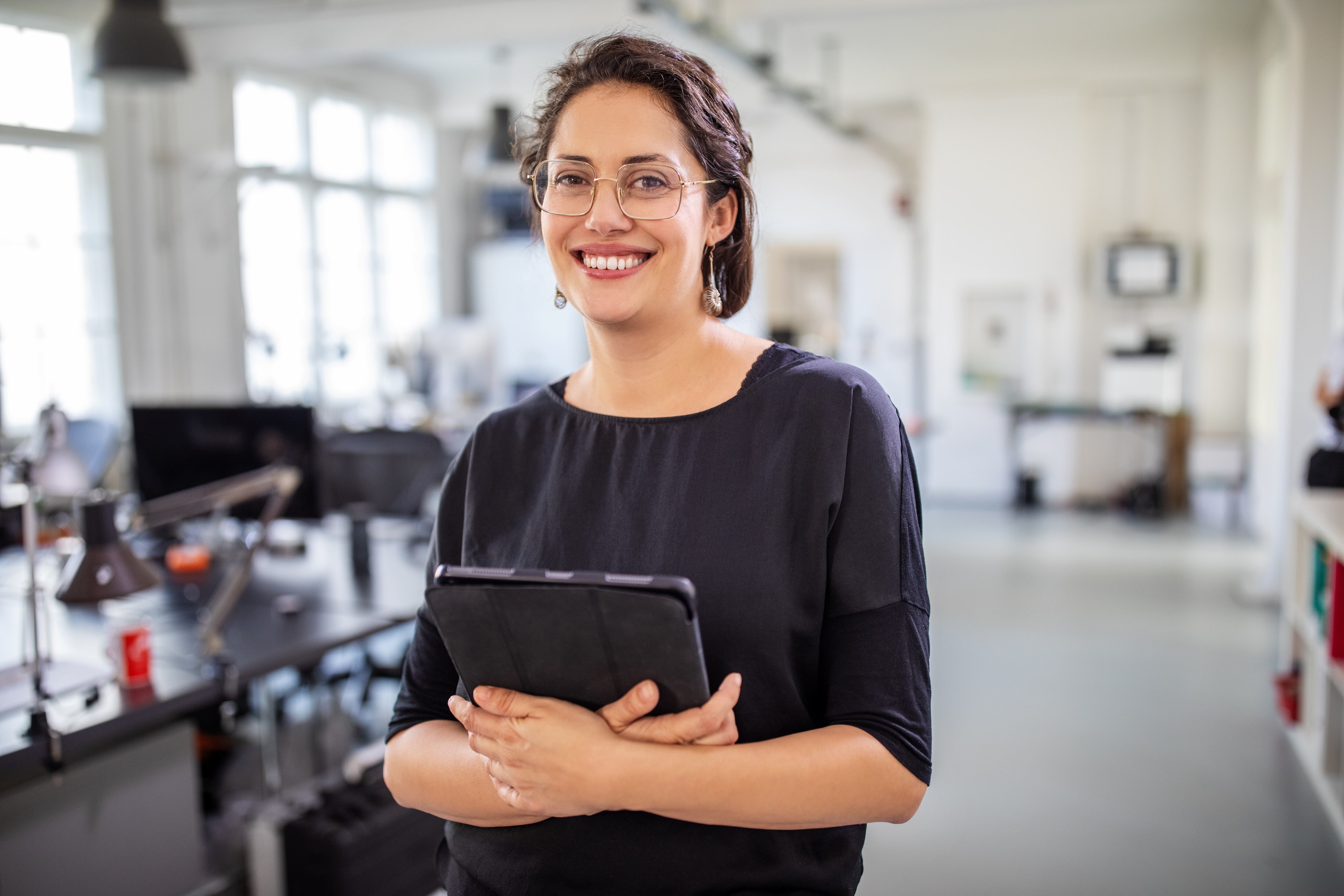 Retrato de una empresaria madura sosteniendo una tableta digital en la oficina. Sonriente mujer profesional de pie en el lugar de trabajo moderno. Empresaria en la oficina con tablet