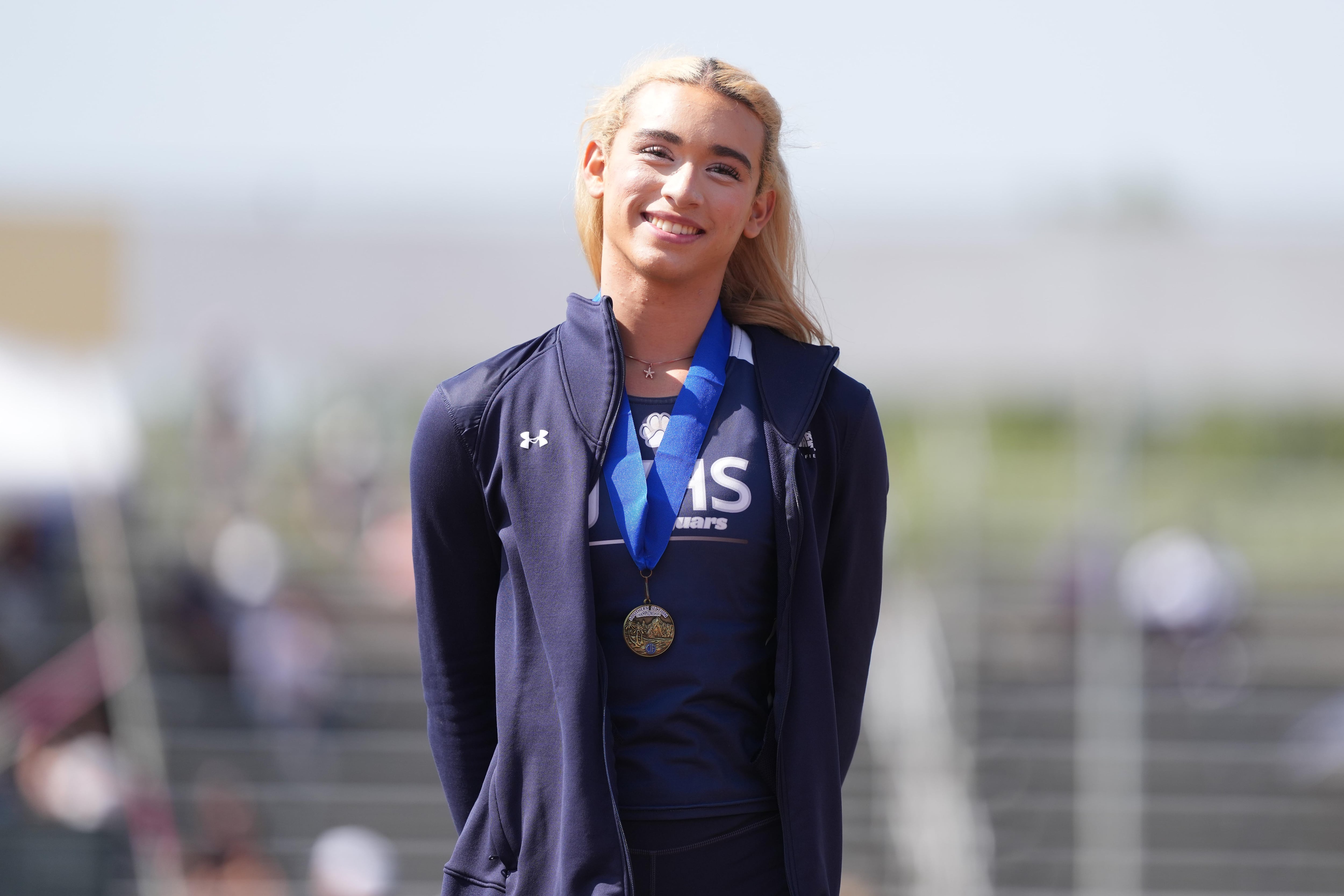 La atleta transgénero AB Hernandez, de Jurupa Valley, posa con la medalla de oro tras ganar la prueba de salto de longitud femenino con una marca de 19 pies y 3 1/2 pulgadas (5,88 m) durante la competición CIF Southern Section Masters Meet en la escuela secundaria Moorpark High School, el 24 de mayo de 2025 en Moorpark, California.