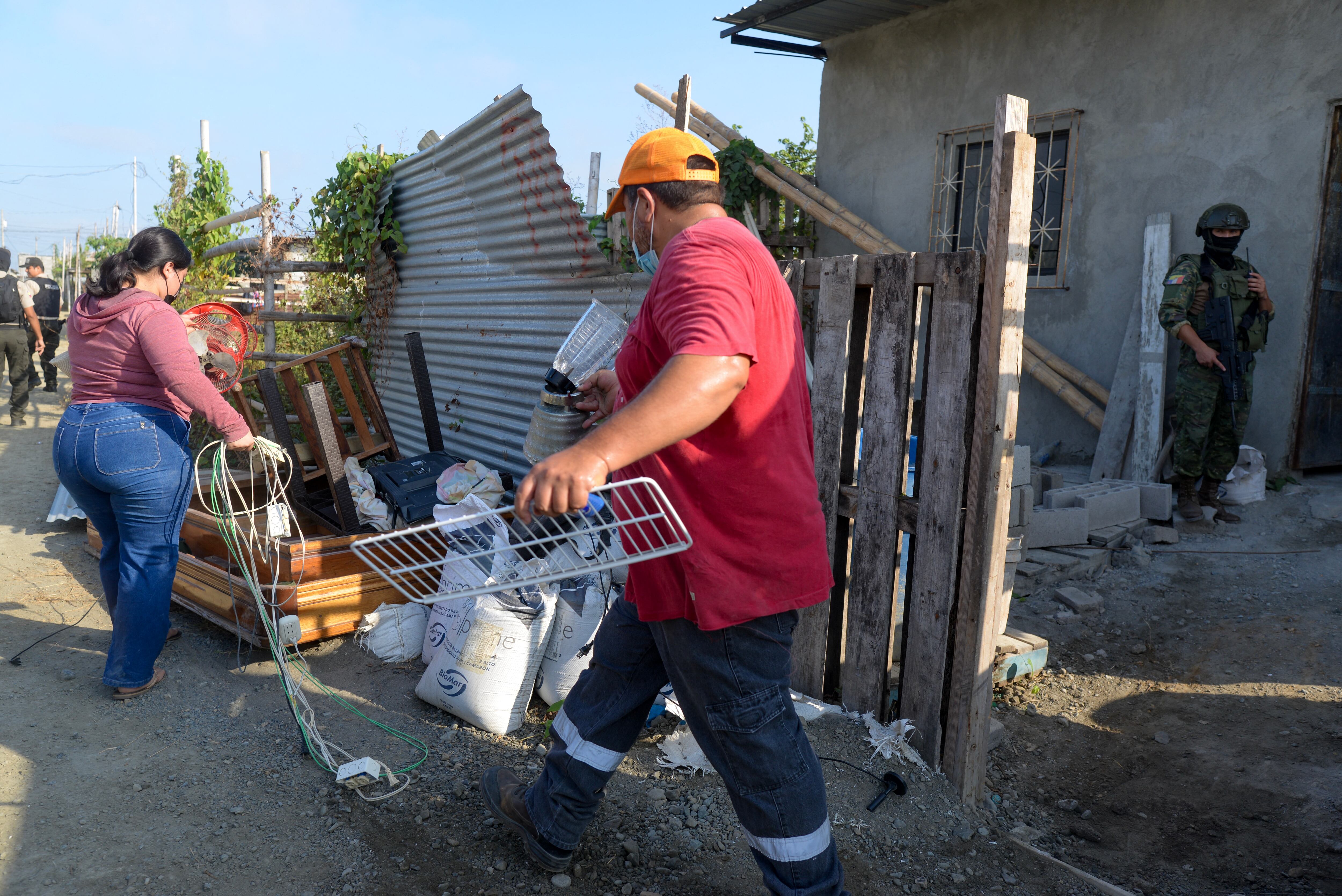 Members of a family remove furniture and belongings from the people who had extorted and evicted them after recovering their house during an operation carried out by the military and police in Duran, 10 km east of Guayaquil, Ecuador, on July 23, 2024. The mood is tense in the violent coastal town of Dur�n, which is guarded by soldiers and police. The small city, located on the banks of the Guayas River, is prized by drug traffickers for its estuaries, which have been converted into river routes to ports from which drugs are shipped. (Photo by Gerardo MENOSCAL / AFP)