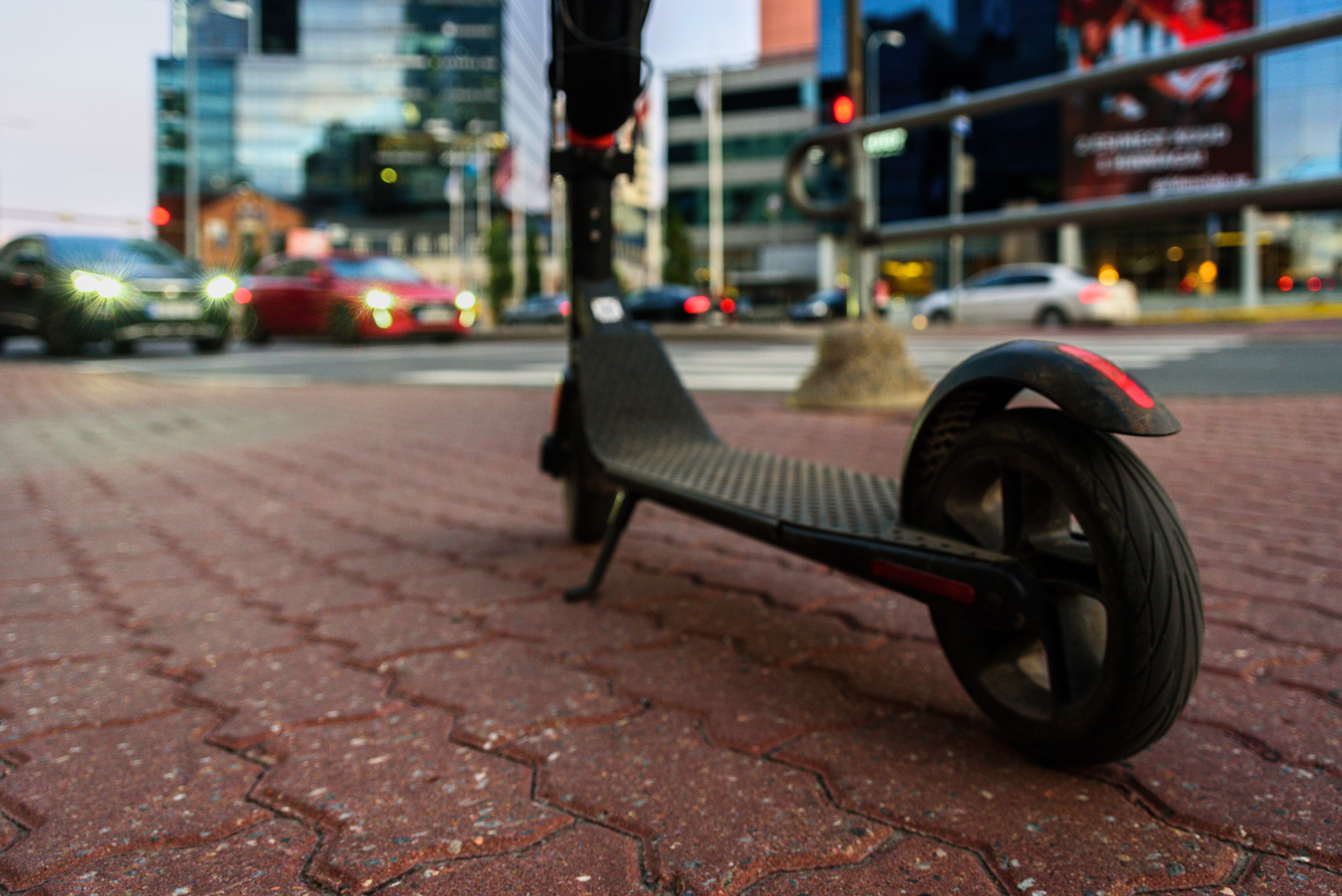 Patineta eléctrica en el moderno distrito de la ciudad con rascacielos. Compartir patineta, alquiler de patineta.