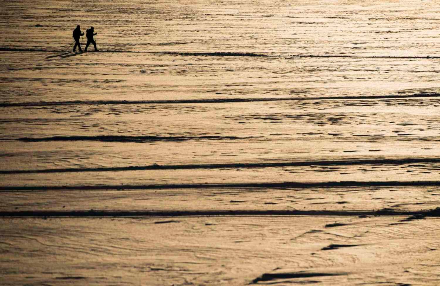 Las personas esquían a través de un lago helado el 2 de febrero de 2018 en Finse. / AFP PHOTO / Jonathan NACKSTRAND