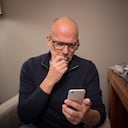 Mature man at home using smartphone for online banking, shopping, social media, e-mail, etc. The serious expression indicates there's something to think about ... phishing, e-mail scam, online abuse, identity theft, who knows what?