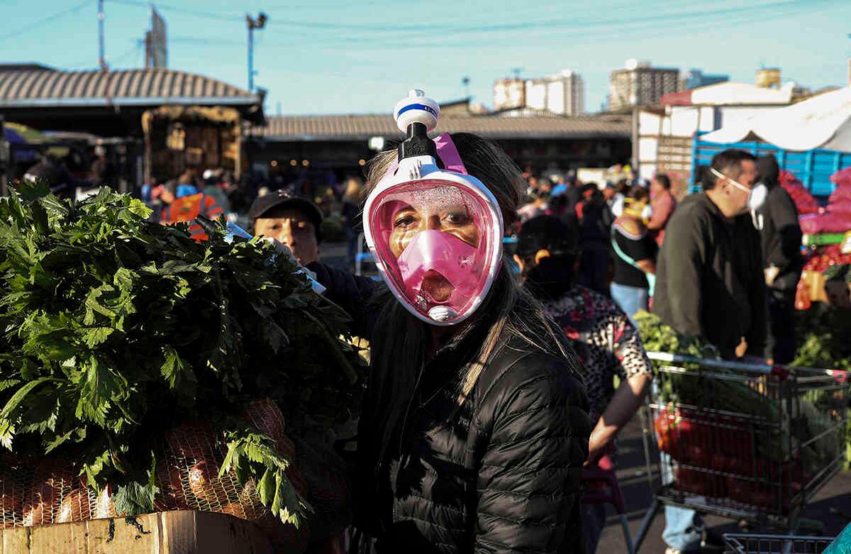 Con los ojos fijos en el lente, una compradora utiliza una máscara de snorkel (actividad de ocio que realizan los buzos) como medida de protección contra el coronavirus mientras compra en el mercado de La Vega, en Santiago, Chile. En Chile, que suma más de 2.500 casos desde que confirmó el primero el 3 de marzo, muchos de los contagios se localizaron en vecindarios de clase media-alta, entre gente que estuvo recientemente en Europa, especialmente en Italia. Foto: Esteban Félix/ AP. 
