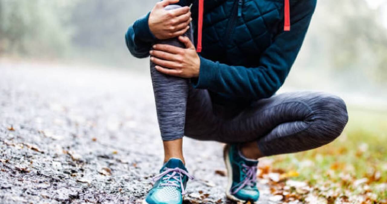 Foto de referencia de mujer haciendo ejercicio y con dolor en su rodilla.
