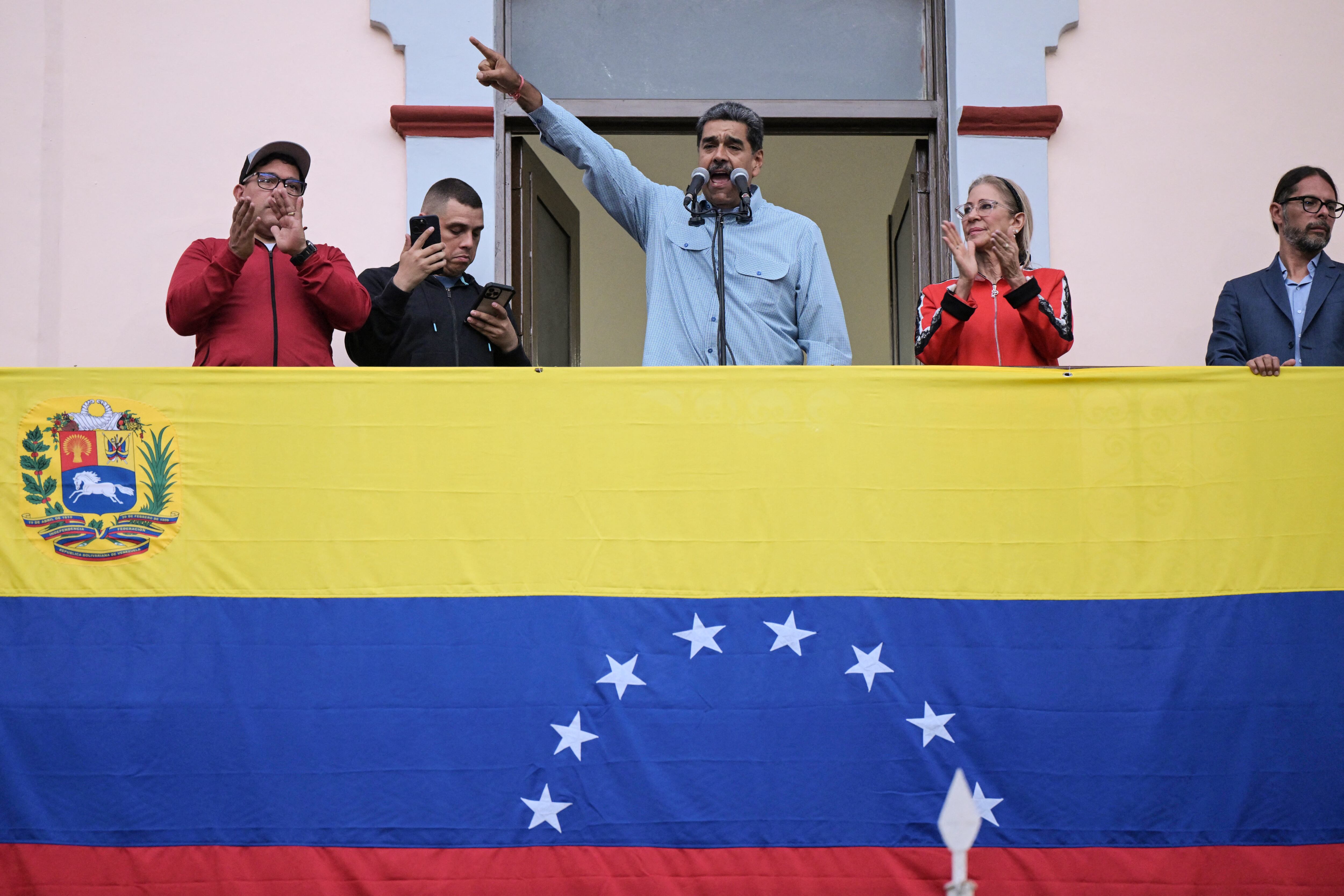 El presidente venezolano, Nicolás Maduro (C), acompañado por su esposa Cilia Flores (C-R), pronuncia un discurso ante sus seguidores durante una manifestación en el palacio presidencial de Miraflores en Caracas el 1 de agosto de 2024. El presidente de Venezuela, Nicolás Maduro, propuso este jueves "retomar" las negociaciones con Estados Unidos, país que no reconoció su reelección y apoya las acusaciones de fraude de la oposición. (Foto de Yuri CORTEZ / AFP)