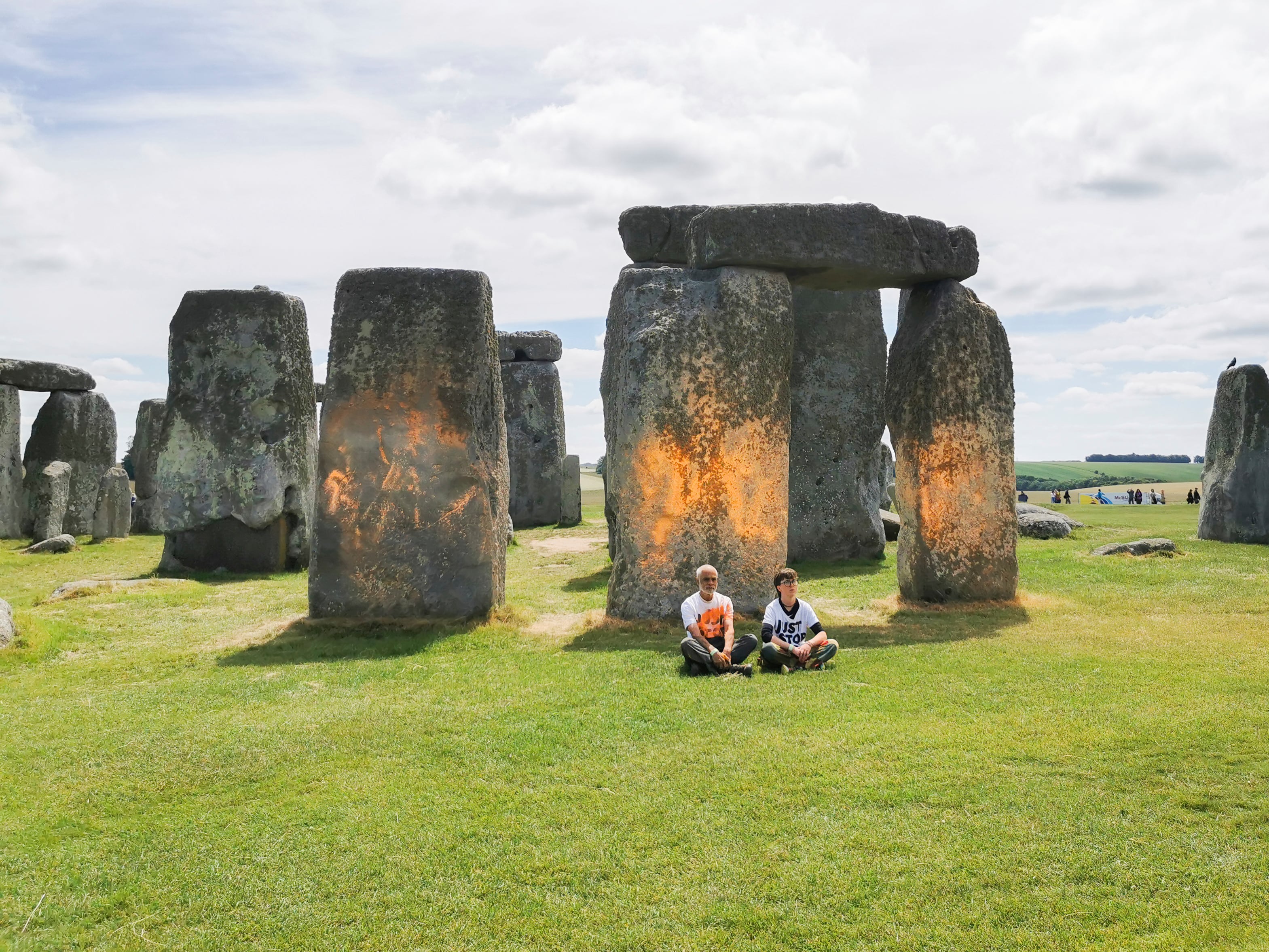En esta foto distribuida, los manifestantes de Just Stop Oil se sientan después de rociar una sustancia naranja en Stonehenge, en Salisbury, Inglaterra, el miércoles 19 de junio de 2024.