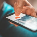 Finger of woman pushing heart icon on screen in mobile smartphone application. Online dating app, valentine's day concept.