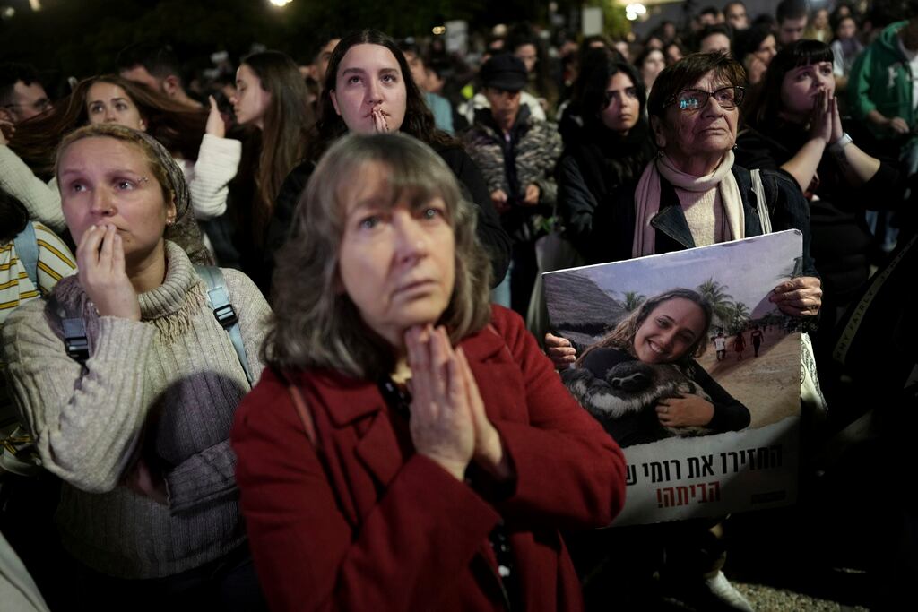 Familiares y amigos de personas asesinadas y secuestradas por Hamas y llevadas a Gaza, uno de ellos con una fotografía de Romi Gonen, reaccionan a la noticia durante una reunión en Tel Aviv, Israel, el domingo 19 de enero de 2025. (Foto AP/ Oded Balilty)