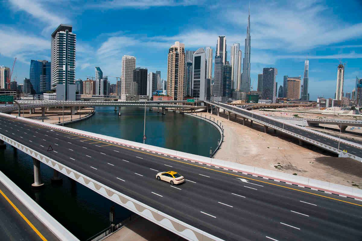 Un taxi recorre una carretera de difícil acceso con el Burj Khalifa, el edificio más alto del mundo, en el horizonte detrás de él, en Dubai, Emiratos Árabes Unidos, el 6 de abril.  Dubai anunció el confinamiento de dos semanas a causa del covid-19. Foto: Jon Gambrell/ AP.