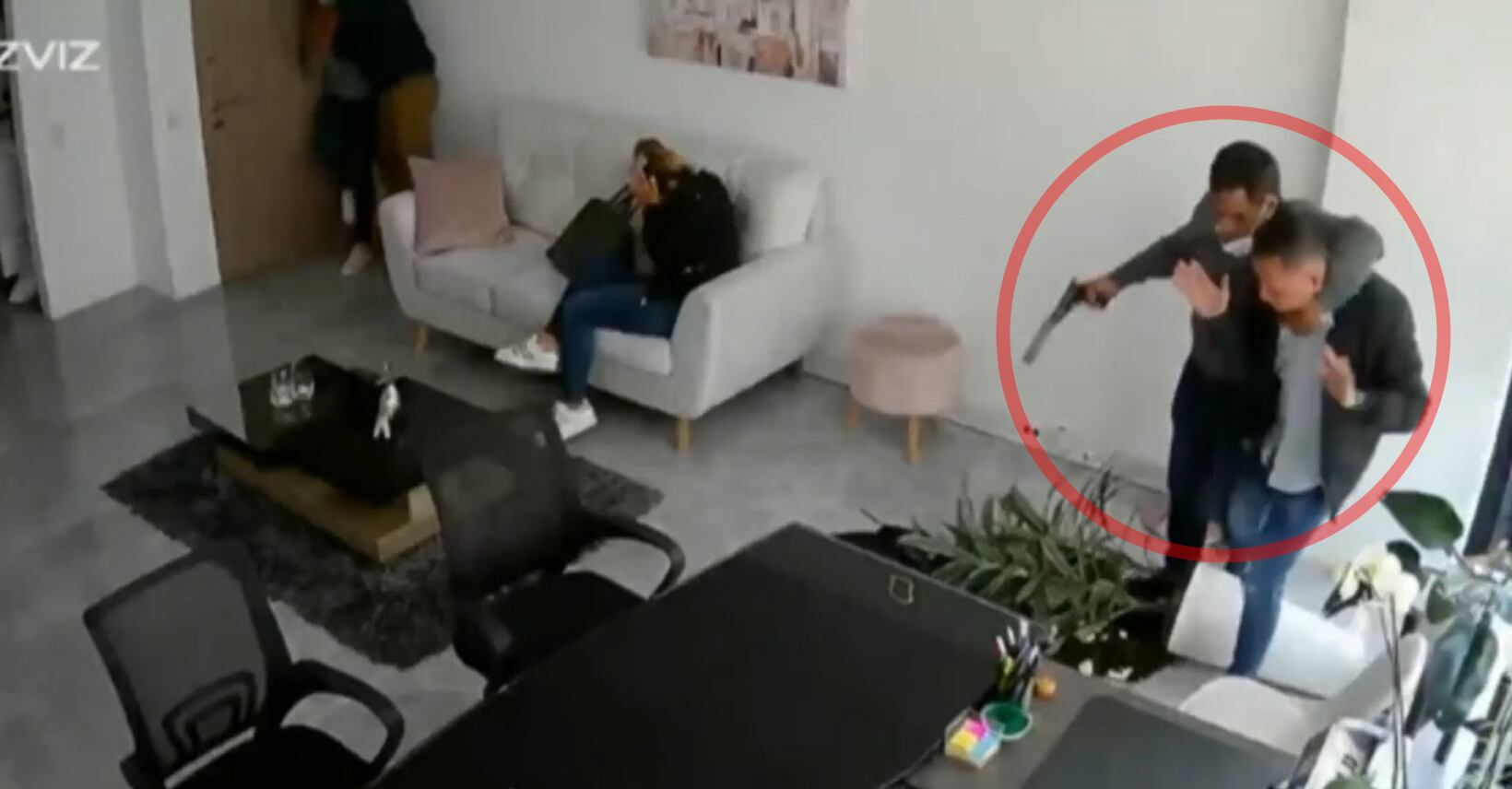 Uno de los delincuentes entra al lugar con un arma.