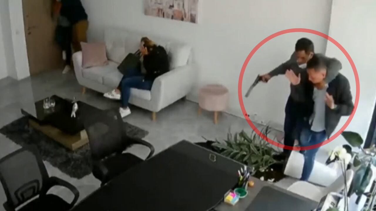 Uno de los delincuentes entra al lugar con un arma.