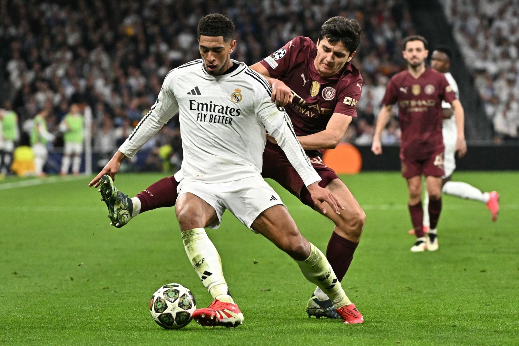 El centrocampista inglés #05 del Real Madrid Jude Bellingham (izq.) es desafiado por el defensa uzbeko #45 del Manchester City Abdukodir Khusanov durante el partido de play-off de la fase eliminatoria de la UEFA Champions League entre el Real Madrid CF y el Manchester City.