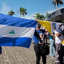 Una mujer sostiene una bandera nacional nicaragüense durante una procesión de la Virgen de Fátima dentro de los terrenos de la Catedral Metropolitana de Managua el 13 de agosto de 2022. - La policía de Nicaragua ha prohibido una procesión prevista por la Iglesia Católica en la capital "por razones de seguridad interna", dijo el viernes la arquidiócesis de Managua. La medida se produce cuando un destacado obispo católico permanece bloqueado dentro de su residencia por la policía. A pesar de la prohibición de la procesión del sábado, la arquidiócesis pidió a los fieles que se dirigieran a la catedral de la capital para "orar por la iglesia nicaragüense". (Foto por Oswaldo RIVAS / AFP)