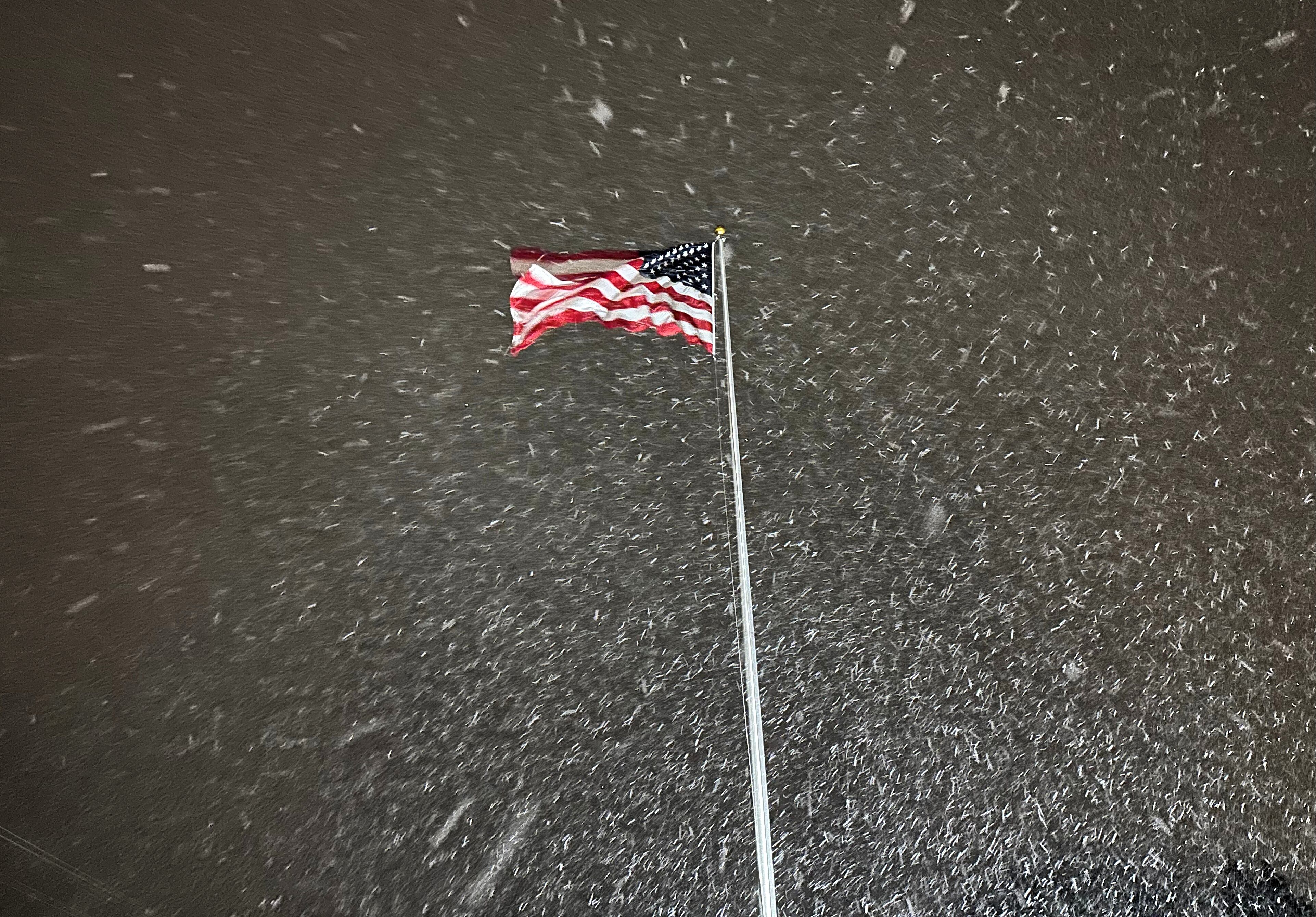 Una bandera ondea en el viento mientras cae nieve en Lowville, Nueva York, la noche del martes 9 de diciembre de 2025