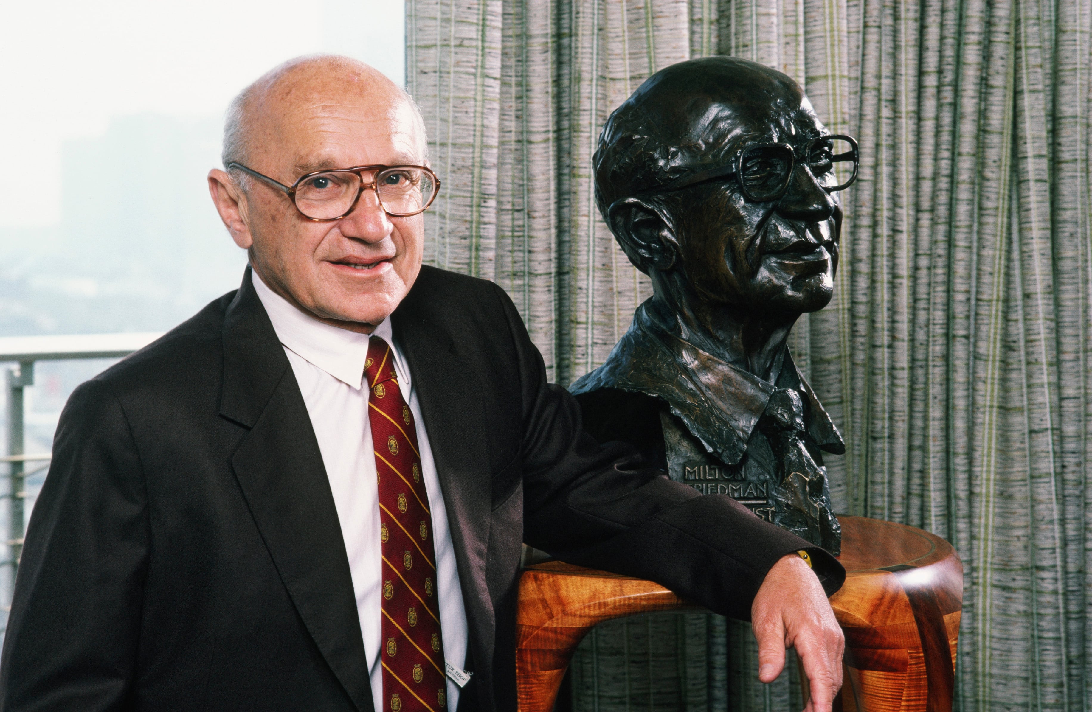 El economista ganador del Premio Nobel Milton Friedman posa con una escultura de sí mismo durante una sesión de retratos fotográficos en 1986 en San Francisco, California.
