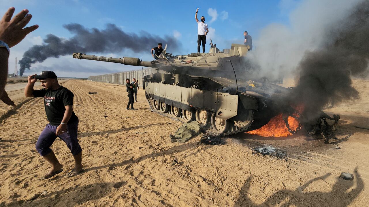Los palestinos celebran junto a un tanque israelí destruido en la valla de la Franja de Gaza al este de Khan Younis, al sur, el sábado 7 de octubre de 2023.