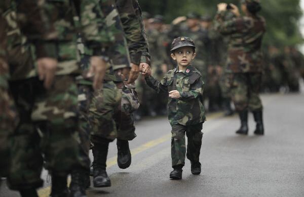 Un niño marcha con su padre, un reservista del ejército de Paraguay, durante el día de la independencia, en Asunción. (AP)