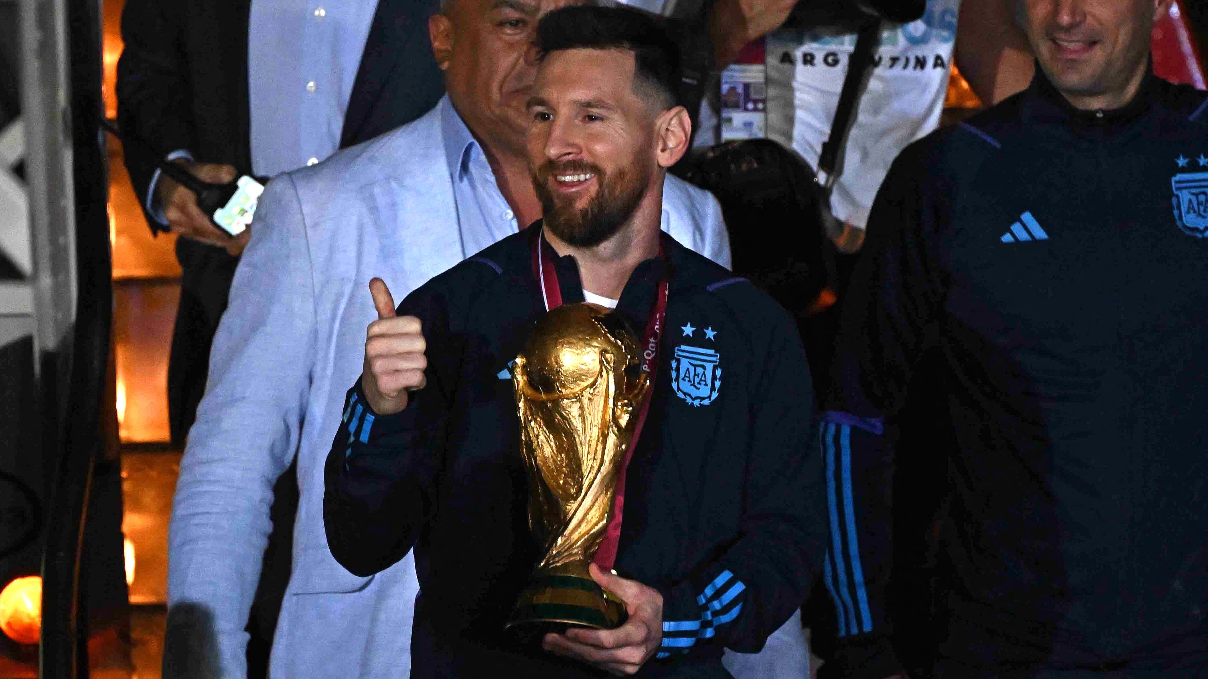 Argentina's captain and forward Lionel Messi (C) holds the FIFA World Cup Trophy alongside Argentina's coach Lionel Scaloni (R) upon arrival at Ezeiza International Airport after winning the Qatar 2022 World Cup tournament in Ezeiza, Buenos Aires province, Argentina on December 20, 2022. (Photo by Luis ROBAYO / AFP)