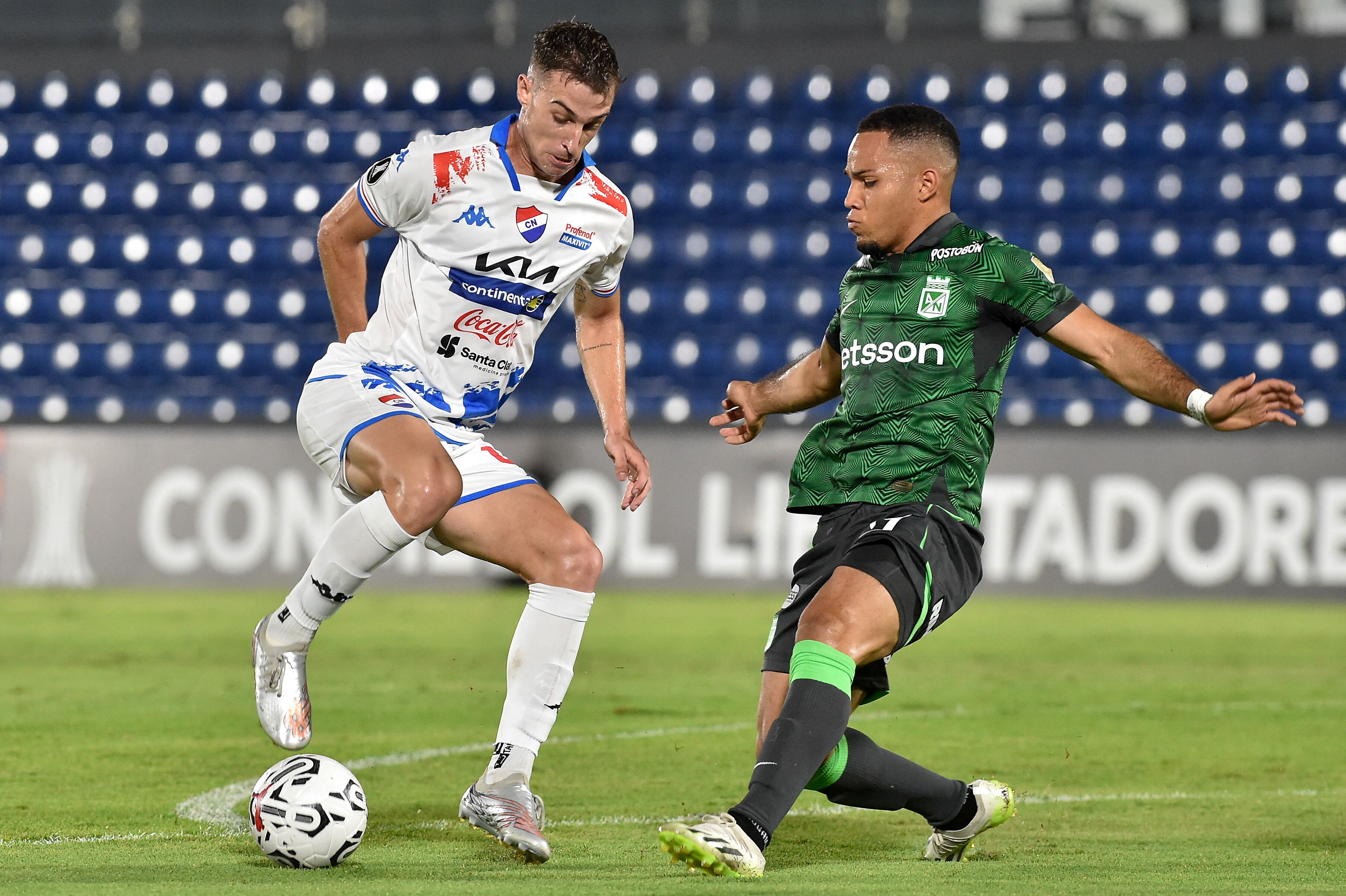 El mediocampista argentino de Nacional Juan Fernando Alfaro (i) y el mediocampista del Atlético Nacional Robert Mejía (d) luchan por el balón durante el partido de ida de la segunda ronda de la Copa Libertadores entre Nacional de Paraguay y Atlético Nacional de Colombia en el estadio Defensores del Chaco en Asunción en febrero 21 de diciembre de 2024. (Foto de NORBERTO DUARTE / AFP)