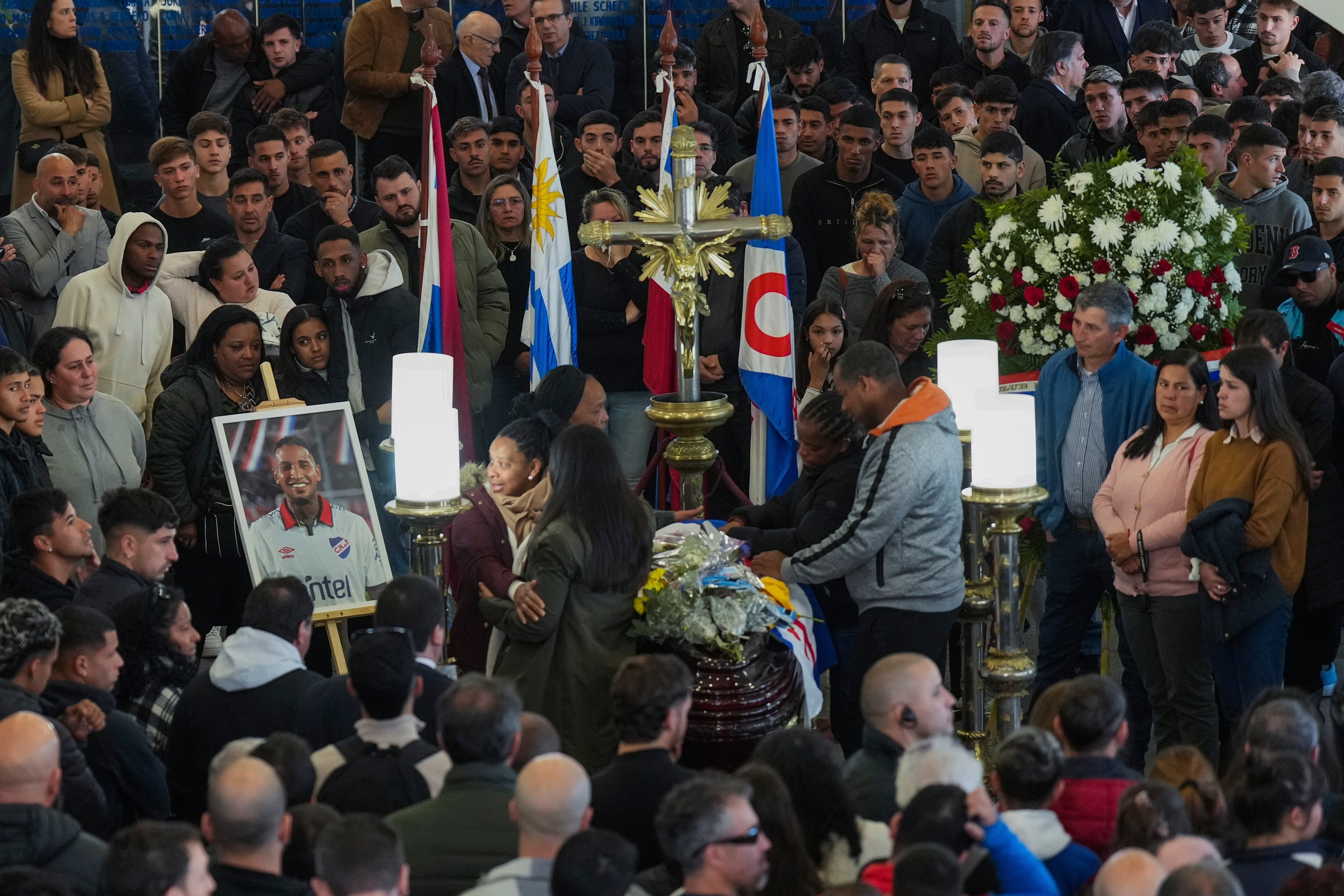 Family members and fans of soccer player Juan Izquierdo gather around his coffin during a wake at his Nacional soccer club in Montevideo, Uruguay, Thursday, Aug. 29, 2024. Izquierdo died at a Brazilian hospital after collapsing on Aug. 22 during a Copa Libertadores soccer match between Nacional and Sao Paulo. (AP Photo/Matilde Campodonico)