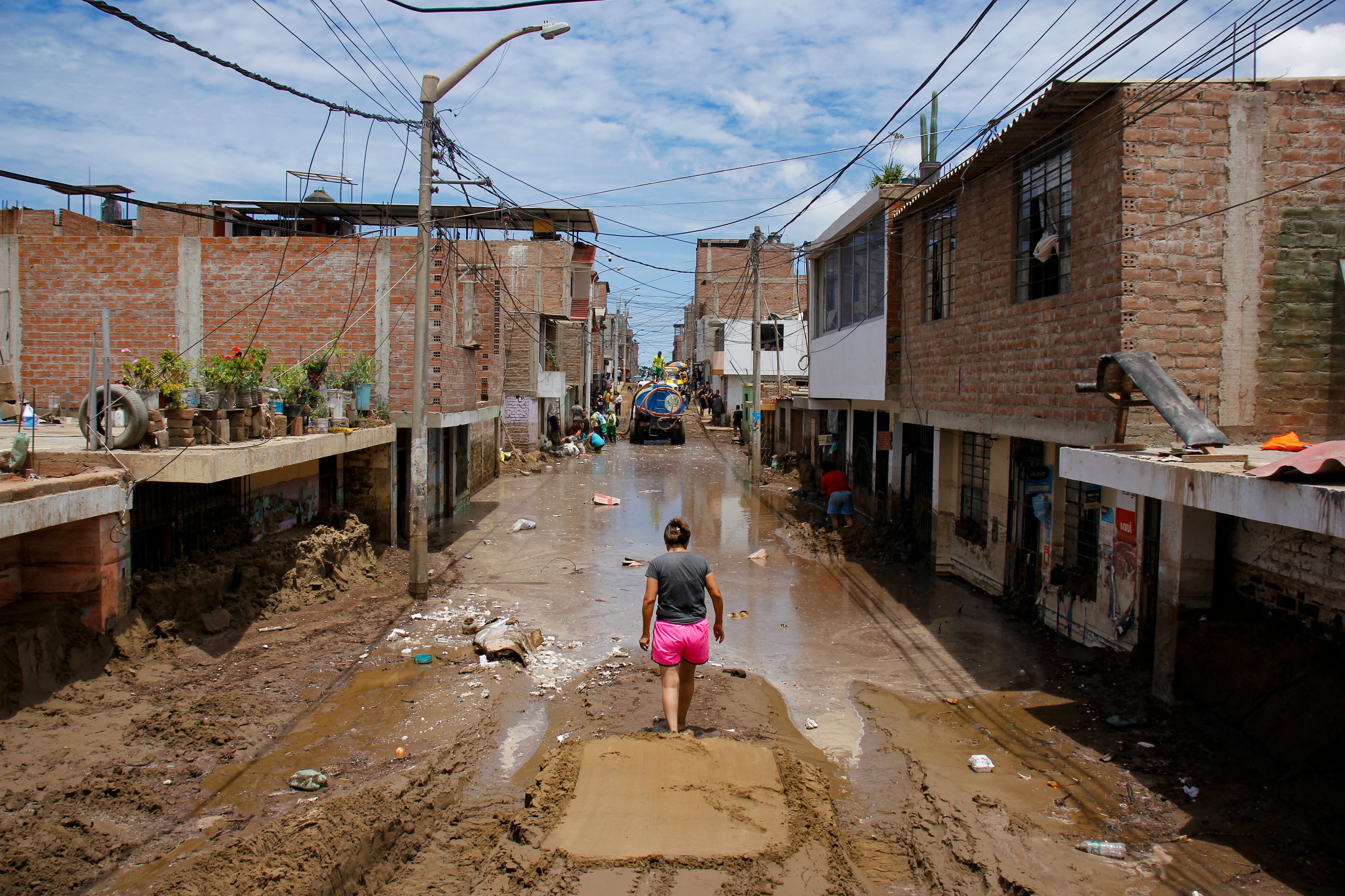 Un residente de La Esperanza, al norte de Trujillo en el Departamento de La Libertad, Perú, camina por una calle inundada -también cubierta de lodo y arena luego de fuertes lluvias provocadas por el ciclón Yaku. (Foto por Arturo GUTARRA / AFP)