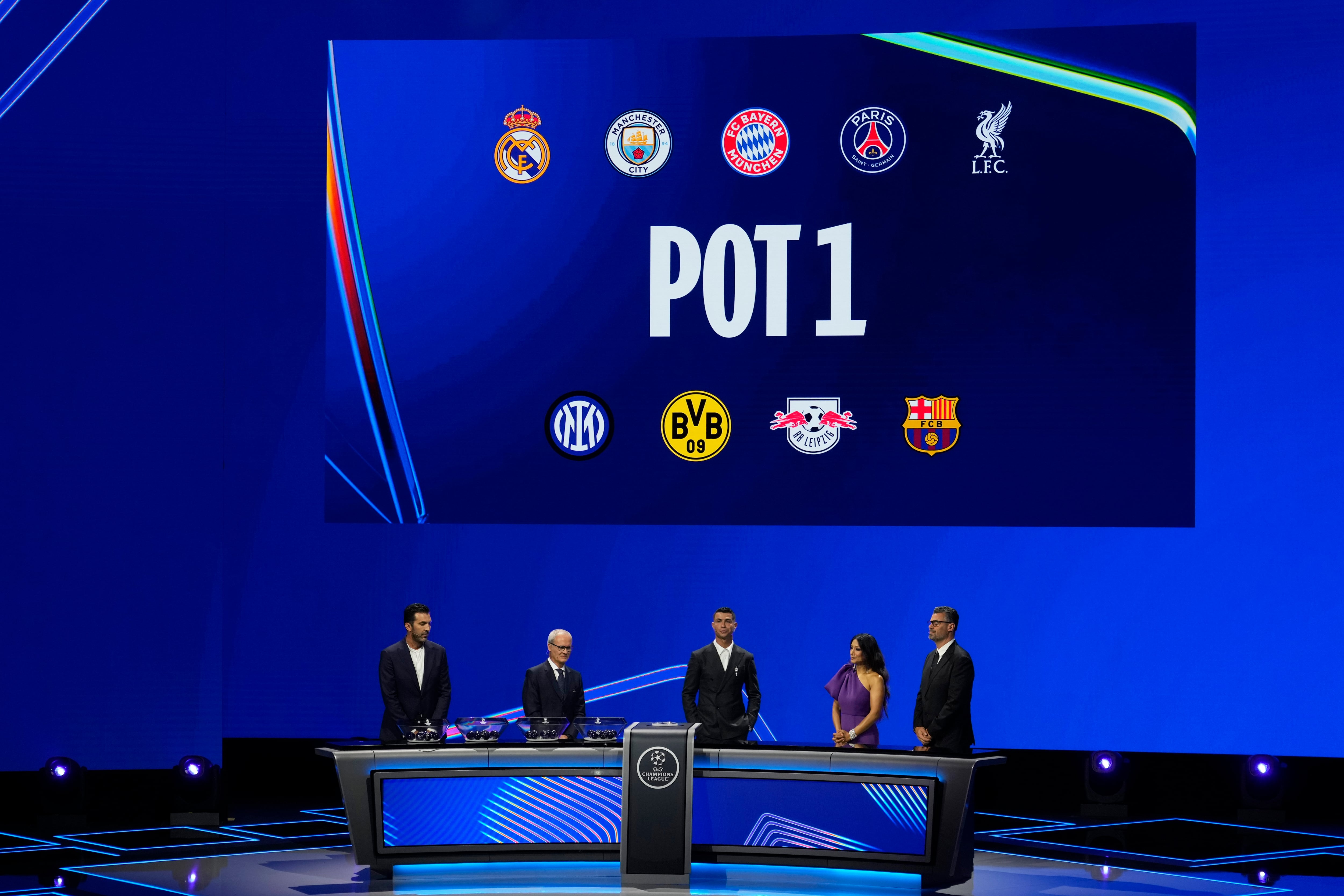The clubs in pot 1 are shown on the screen as former Italian goalkeeper Gianluigi Buffon, UEFA's Giorgio Marchetti and player Cristiano Ronaldo, from left, present the Champions League, league phase, draw, in Monaco, Thursday, Aug. 29, 2024. (AP Photo/Gregorio Borgia)