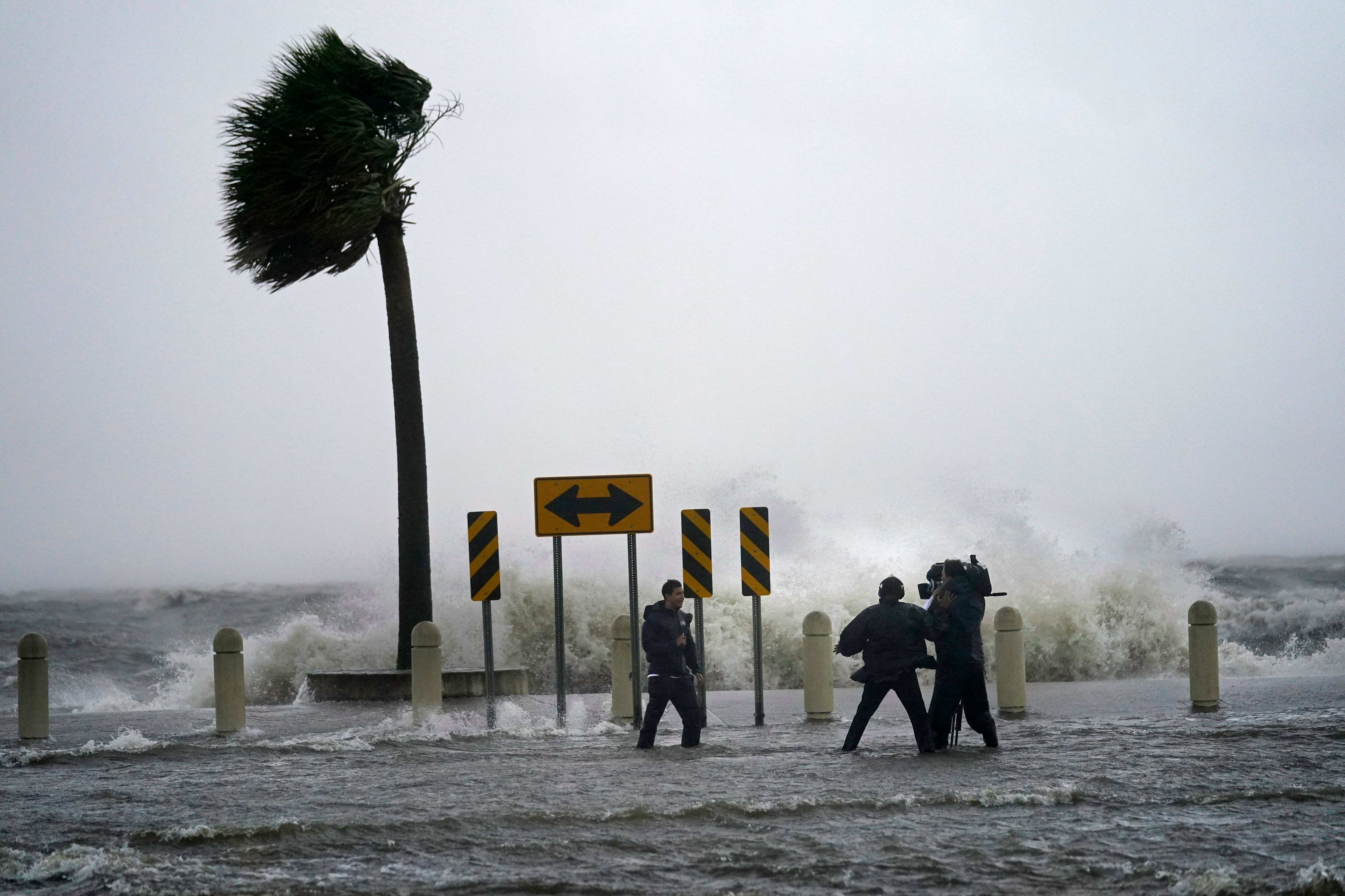 Un equipo de reporteros y camarógrafos cerca del lago Pontchartrain, en Nueva Orleans, el domingo 29 de agosto de 2021, previo a la llegada del huracán Ida. (AP Foto/Gerald Herbert)