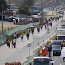 Commuters walk along an avenue blocked by truckers protesting a government-announced increase in diesel prices in Bogota, Colombia, Tuesday, Sept. 3, 2024. (AP Photo/Fernando Vergara)