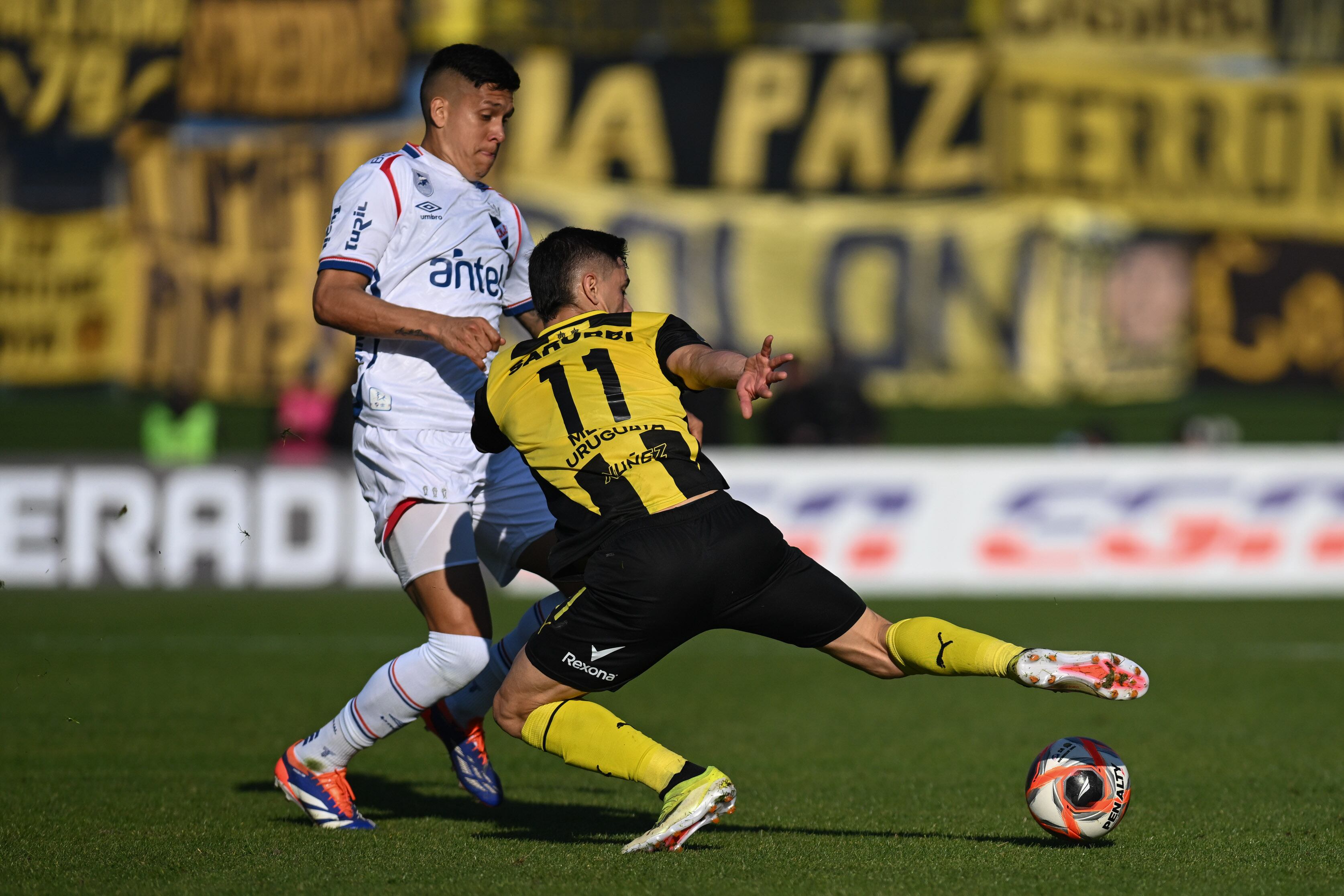 Julián Millán (blanco) en un clásico con Nacional de Uruguay ante Peñarol.