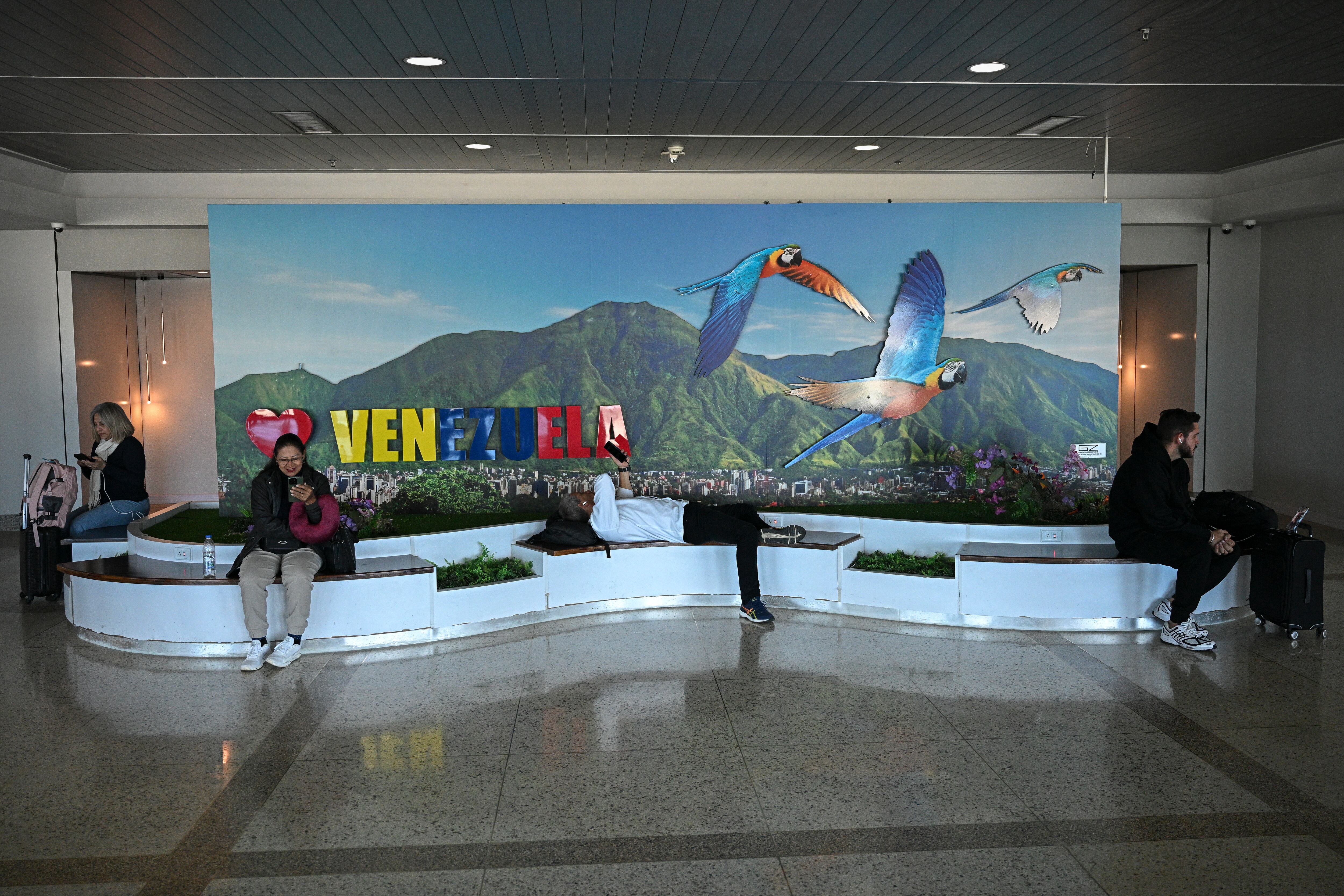 People rest near a boarding gate at the Simon Bolivar International Airport in Maiquetia, La Guaira State, Venezuela, on November 30, 2025. US President Donald Trump sharply escalated his threats against Venezuela on Saturday with an ominous warning that the country's airspace should be considered "closed," raising fears of imminent military action. (Photo by Federico PARRA / AFP)