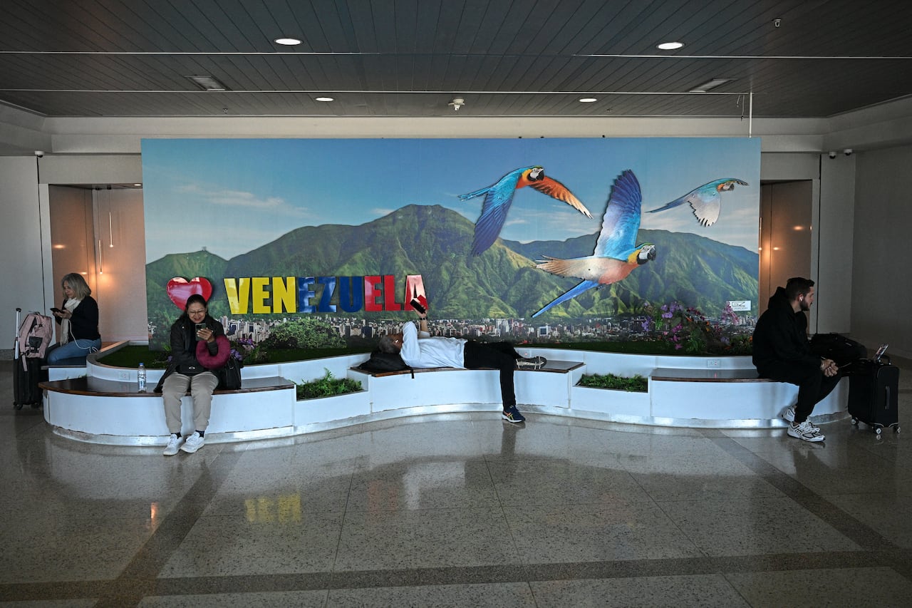 People rest near a boarding gate at the Simon Bolivar International Airport in Maiquetia, La Guaira State, Venezuela, on November 30, 2025. US President Donald Trump sharply escalated his threats against Venezuela on Saturday with an ominous warning that the country's airspace should be considered "closed," raising fears of imminent military action. (Photo by Federico PARRA / AFP)