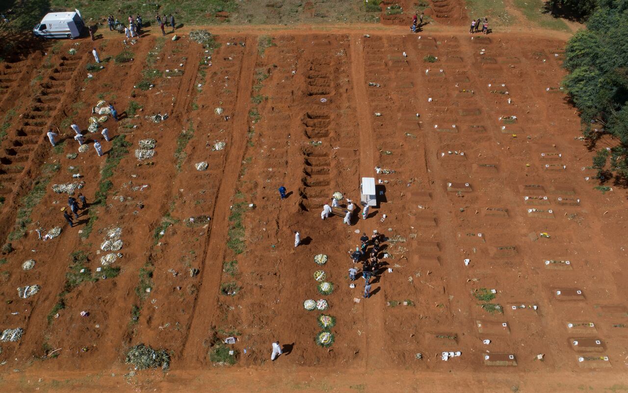Empleados de cementerio con vestimenta protectora cargan el ataúd con los restos de una persona que murió de complicaciones derivadas del COVID-19 en el cementerio Vila Formosa, Sao Paulo, Brasil. (AP Foto/Andre Penner)