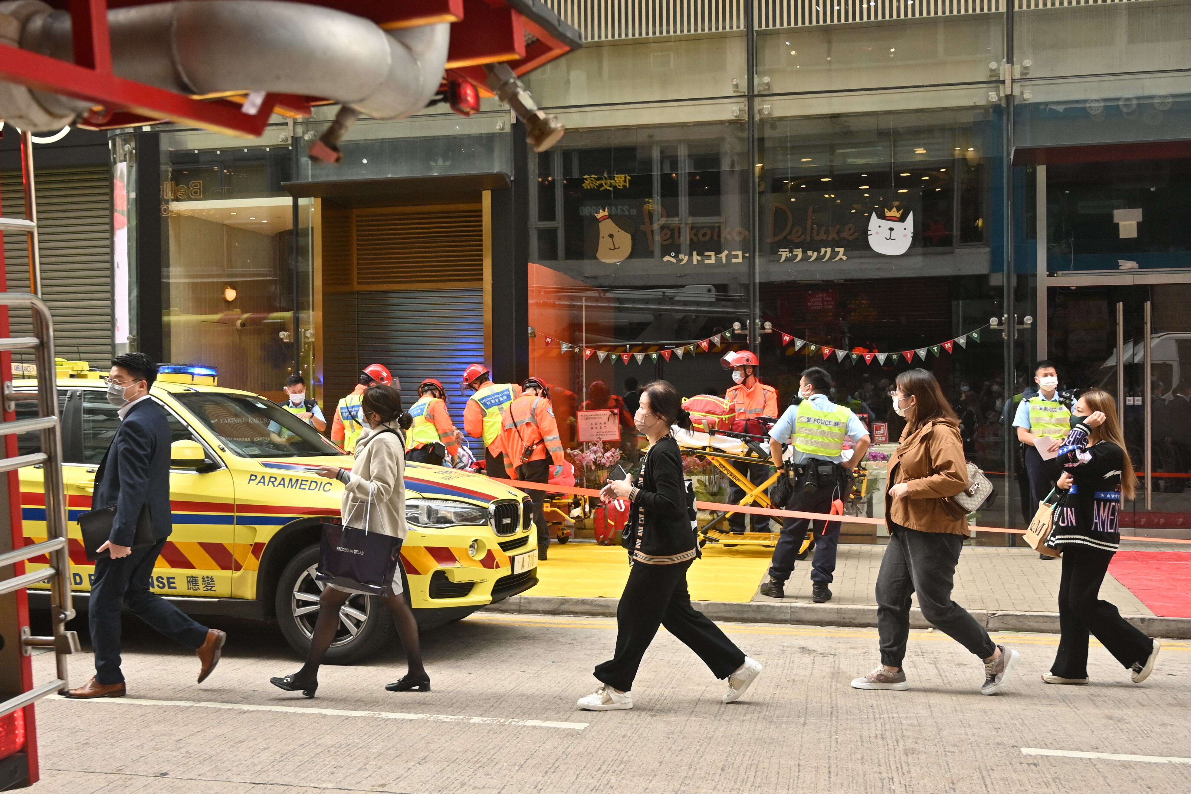 La gente pasa junto a los trabajadores de rescate luego del incendio en el edificio del World Trade Center de 38 pisos, que sufrió un incidente eléctrico que atrapó a cientos en la azotea, en el distrito de Causeway Bay de Hong Kong (Photo by Peter PARKS / AFP)