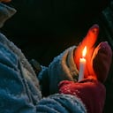 Una mujer protege una vela de la nieve que cae durante la Vigilia de oración por la paz en Ucrania y el mundo el jueves 10 de marzo de 2022 por la noche. (Amanda Haverstick/The News Dispatch via AP)