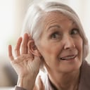 Senior Caucasian woman cupping her ear to listen